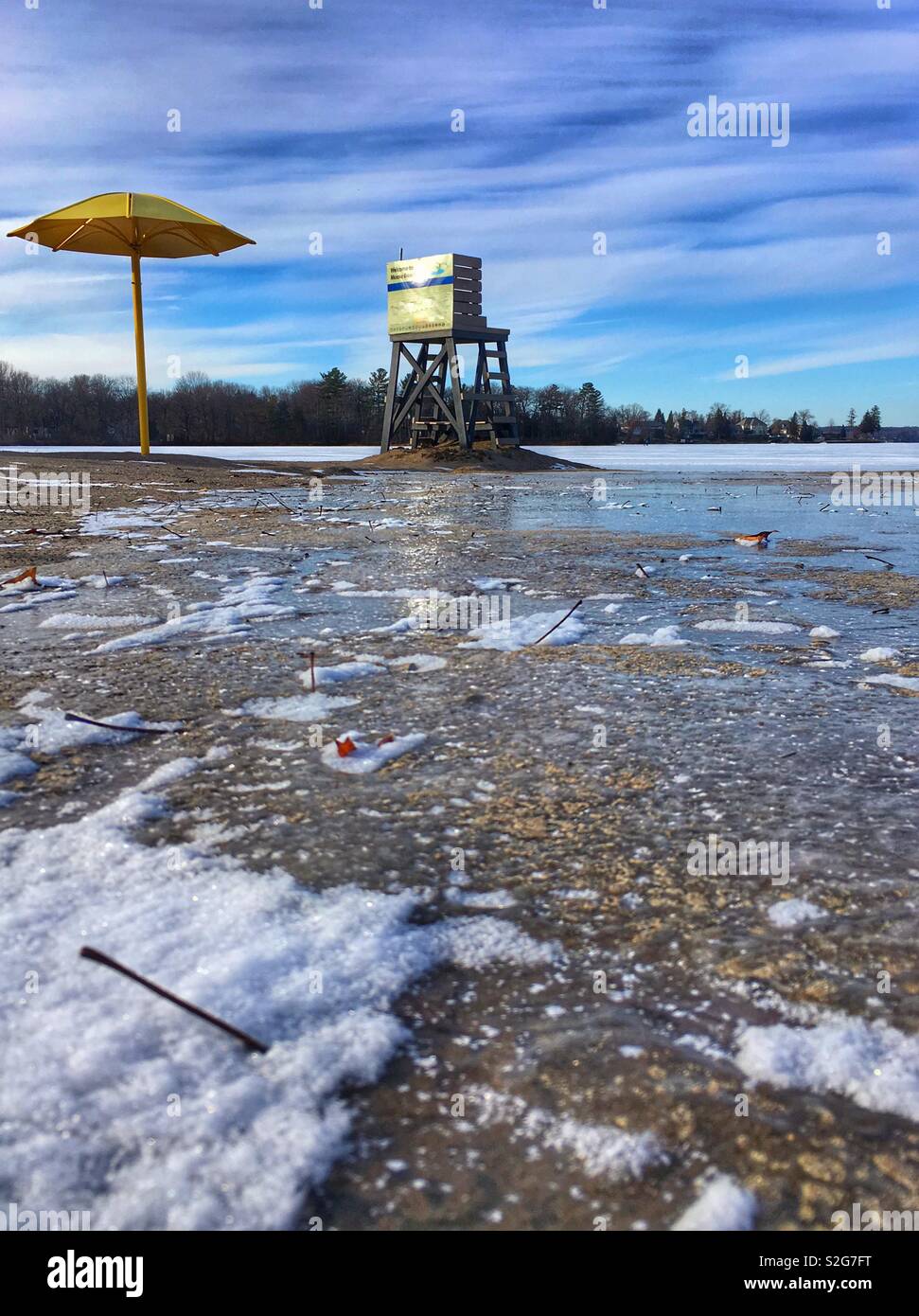 Plage d'hiver, parapluie, secours, lac gelé, et le reflet dans l'accumulation d'eau sur la plage Banque D'Images