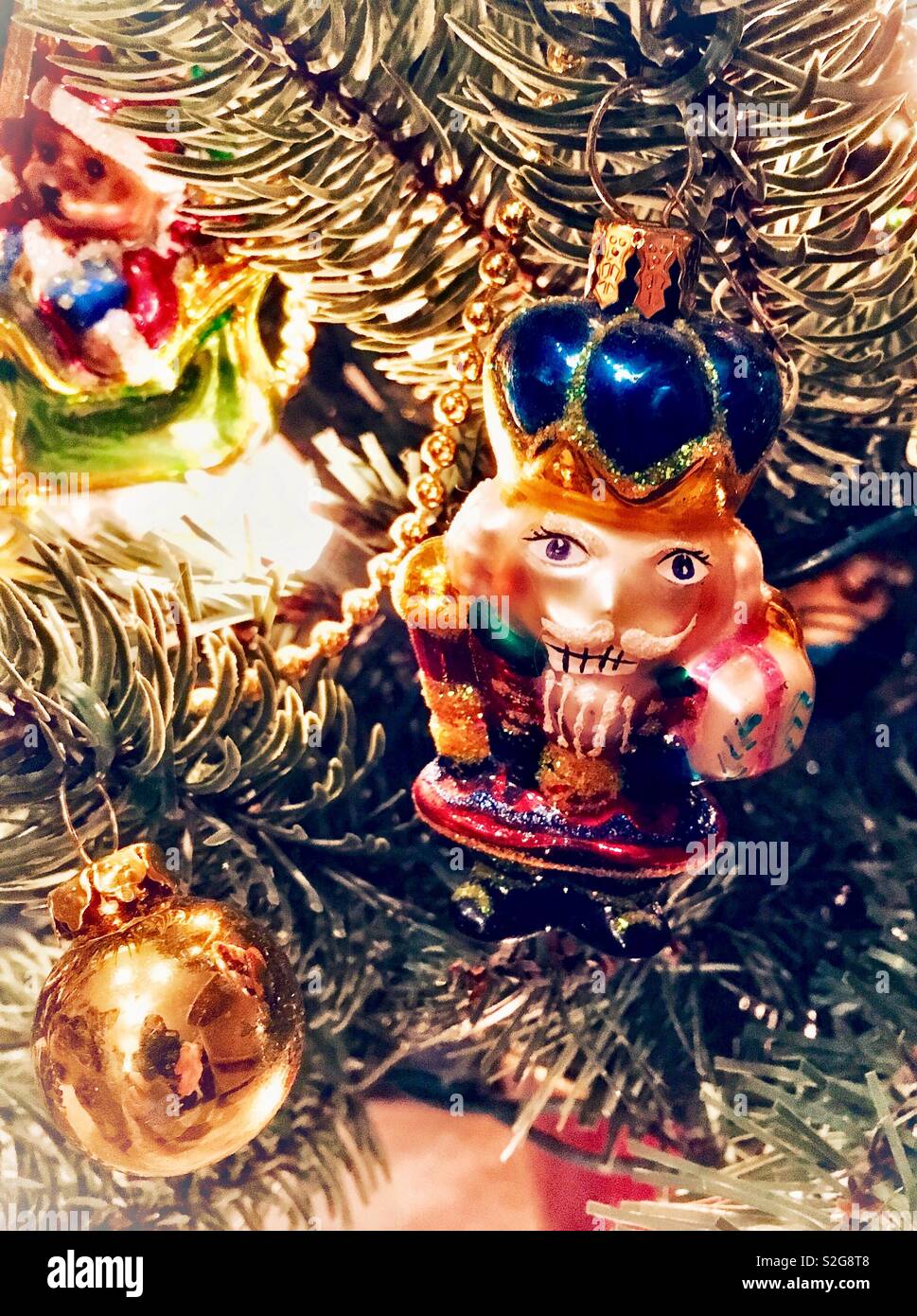 Verre soufflé animé Casse-noisette ornement sur arbre de Noël artificiel avec gold ball ornament et Santa ours ornement en verre - Image de stock capturée avec un smartphone