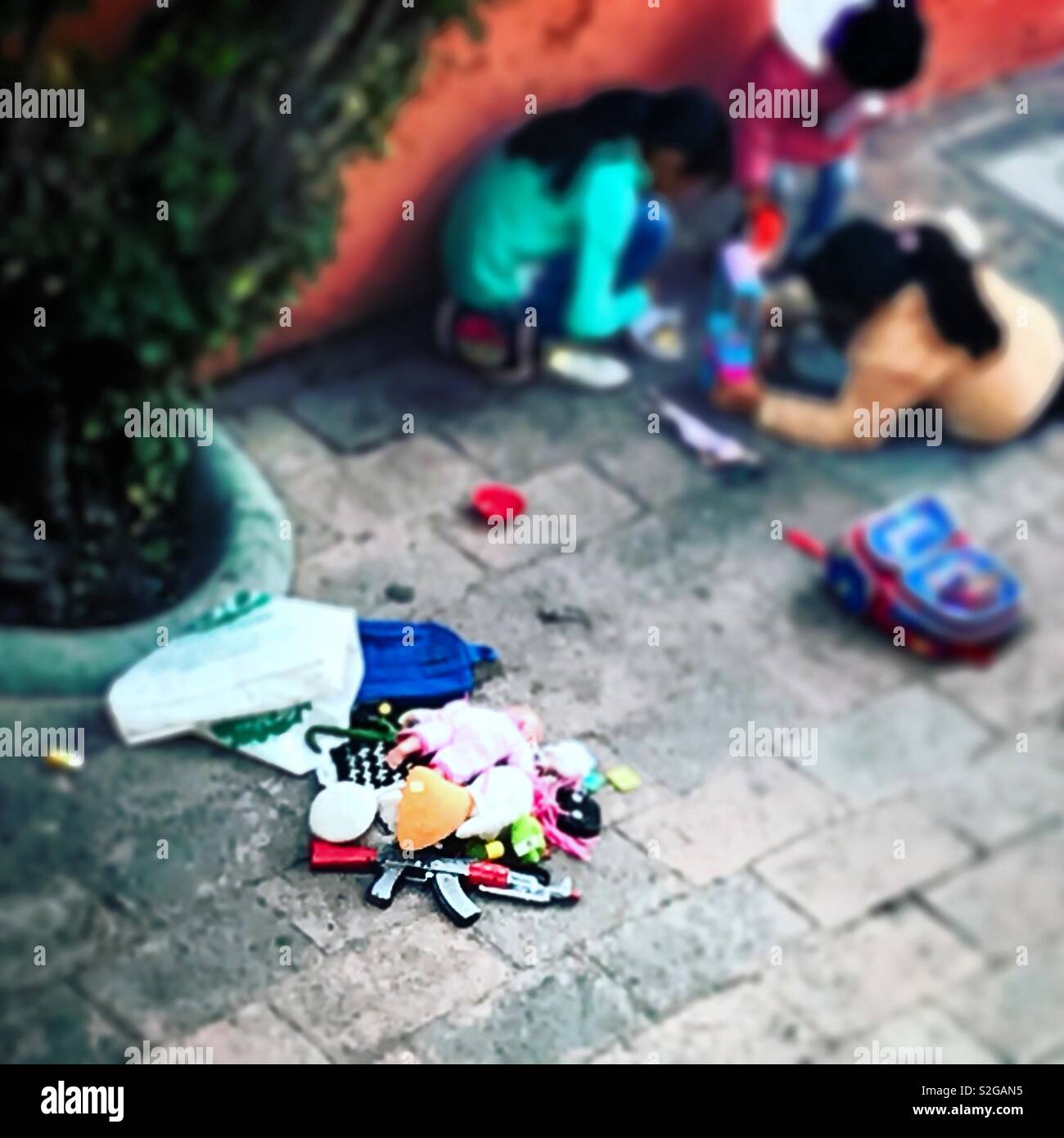 Les enfants jouent avec des jouets à proximité d'un toy machine gun à Tequisquiapan, Queretaro, Mexique Banque D'Images