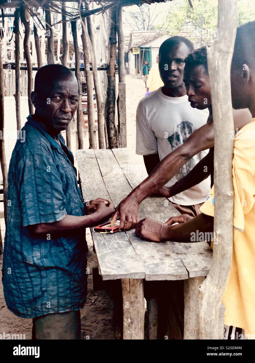 Les hommes malgaches trading et de discuter le prix d'une carte mémoire sur une table en bois au marché de la rue d'Andavadoaka, Madagascar. Banque D'Images