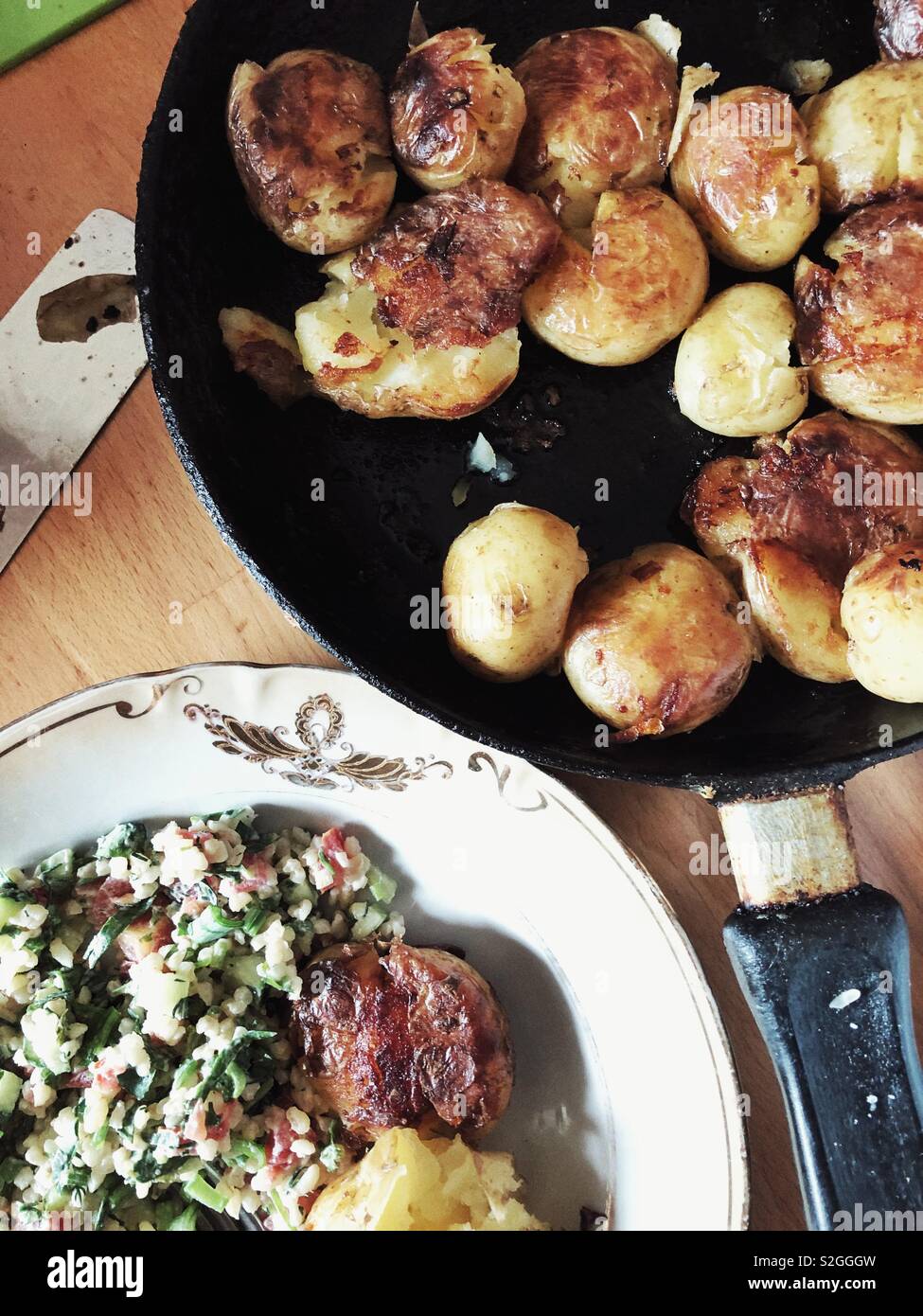 Pommes de terre rôties sur un poêle de fer sur un taboulé frais et plaque fantaisie top view Banque D'Images