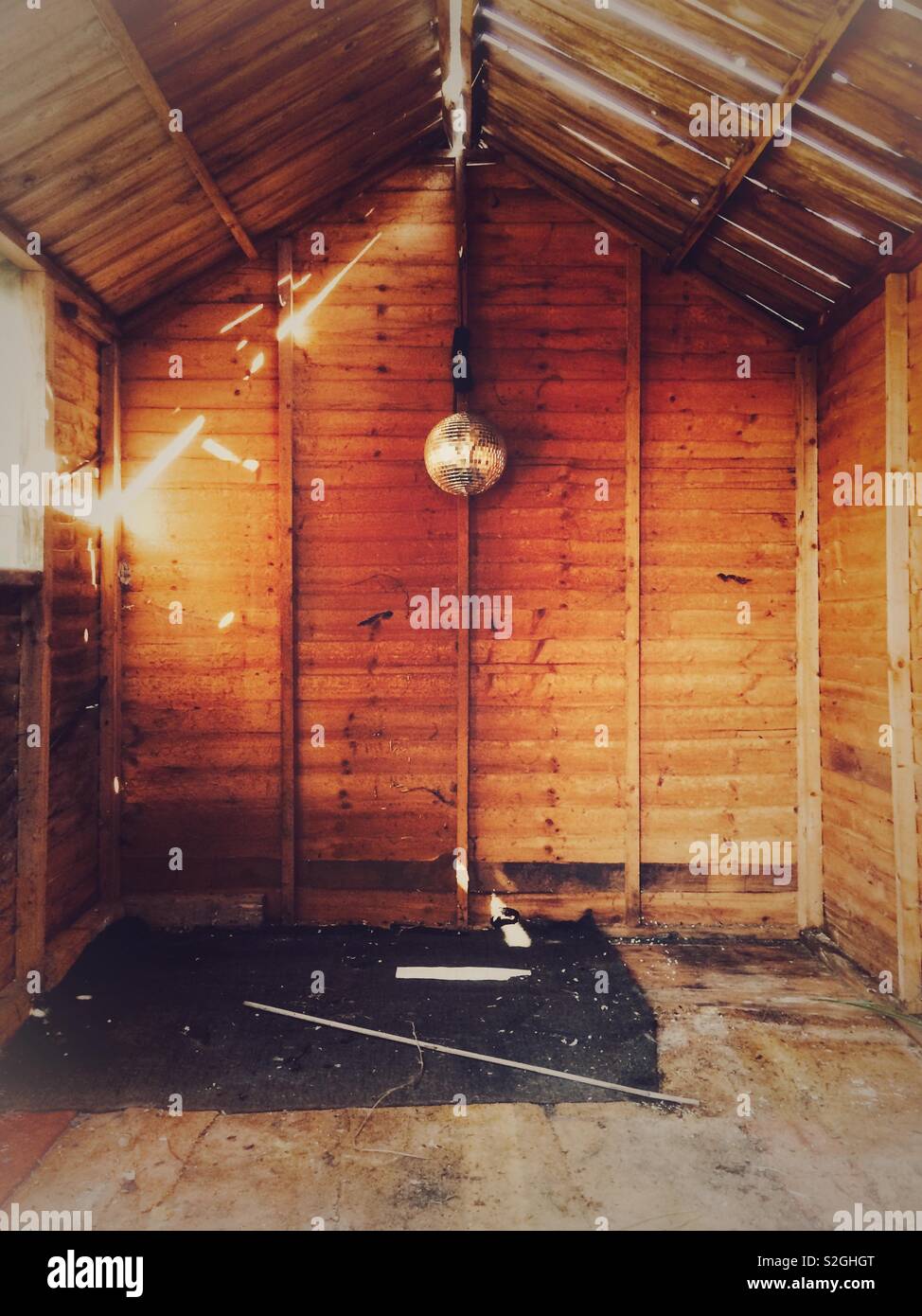 Une cabane en bois délabrée et vide avec un mirrorball accroché au mur arrière Banque D'Images