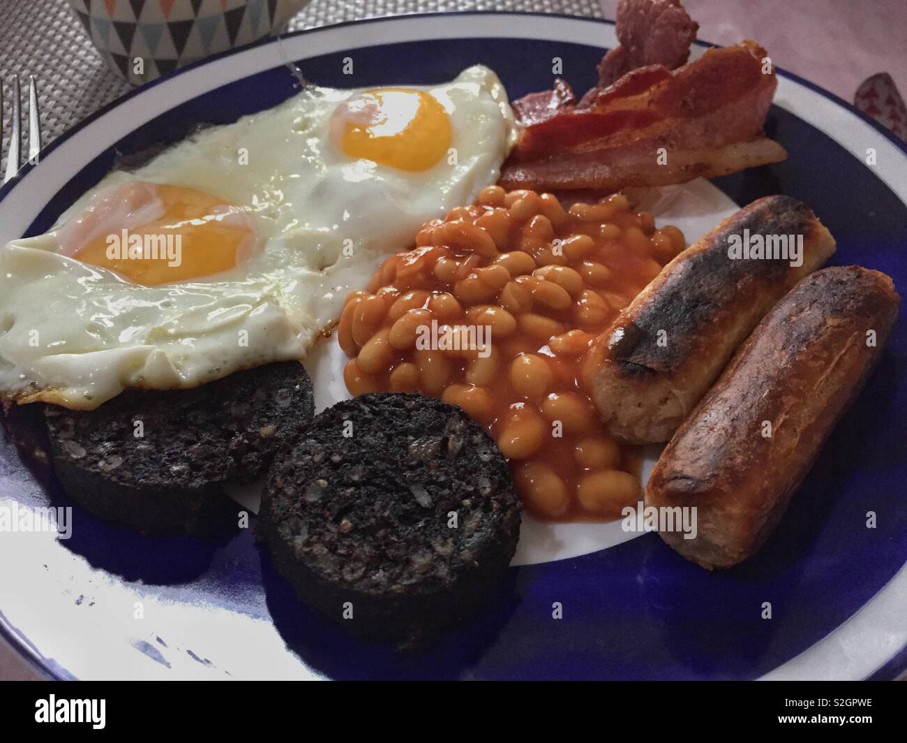 Un petit-déjeuner anglais complet avec œufs frits, des fèves, des saucisses. bacon et du boudin noir. Banque D'Images