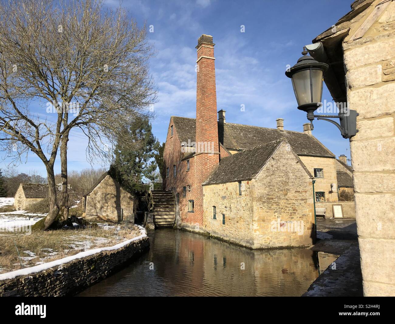 Historique pittoresque moulin à eau sur la rivière Œil à Lower Slaughter dans les Cotswolds, avec sa roue à eau et préservés sur mill race un jour de neige. - Image de stock capturée avec un smartphone