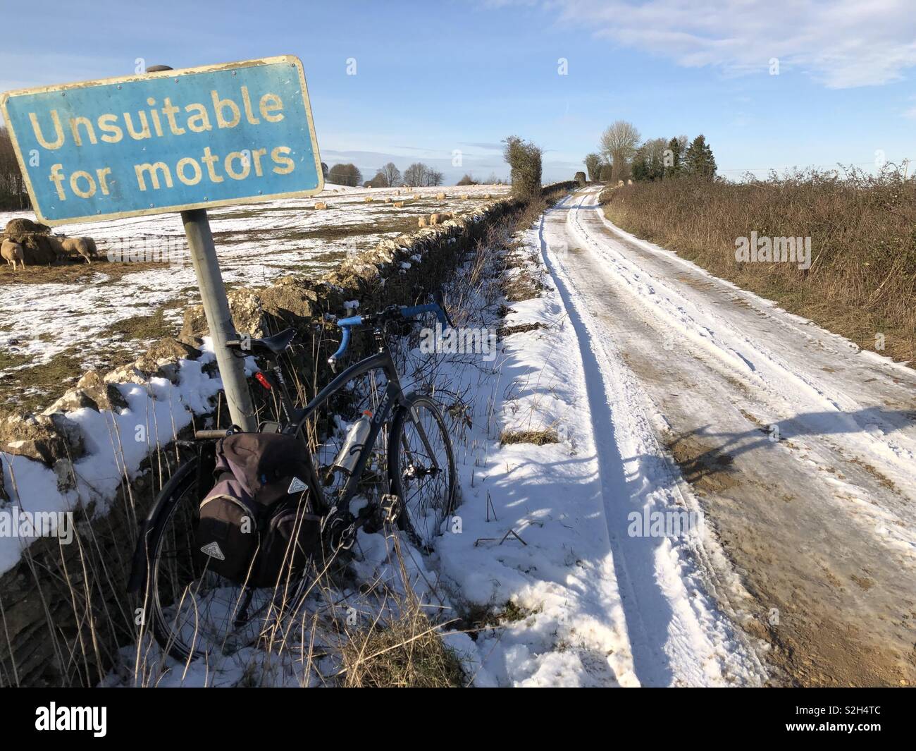 Vélo aventure en hiver profonde dans les Cotswolds, sur une ancienne voie romaine couverte de neige montrant un vélo prêté contre un panneau disant 'impropres à motors'. Banque D'Images