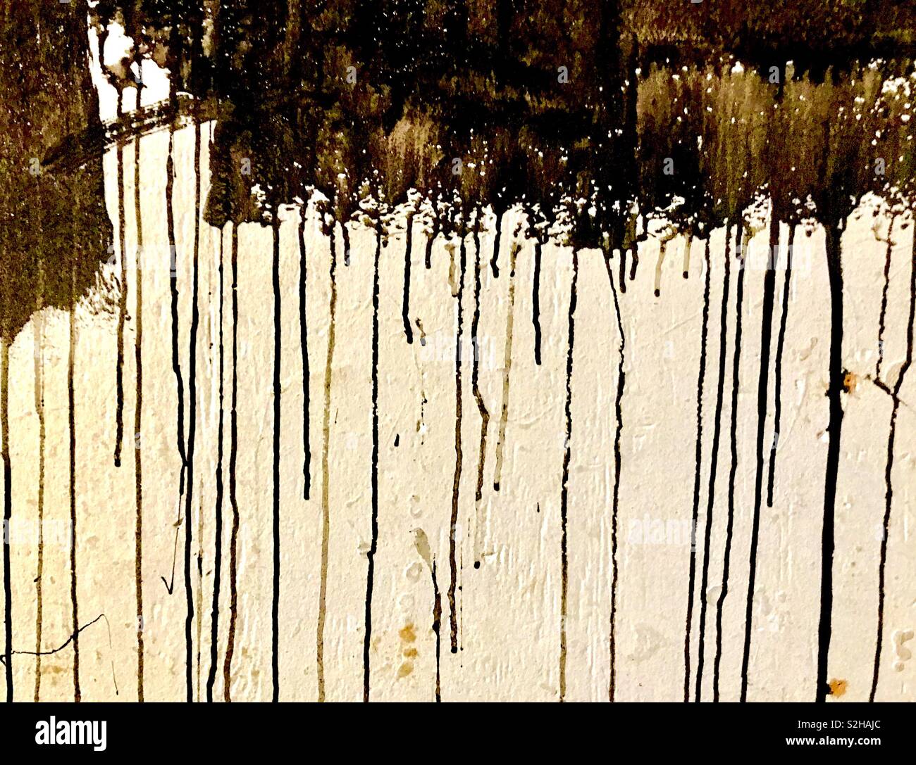 Les gouttes de peinture noire sur un mur. Banque D'Images