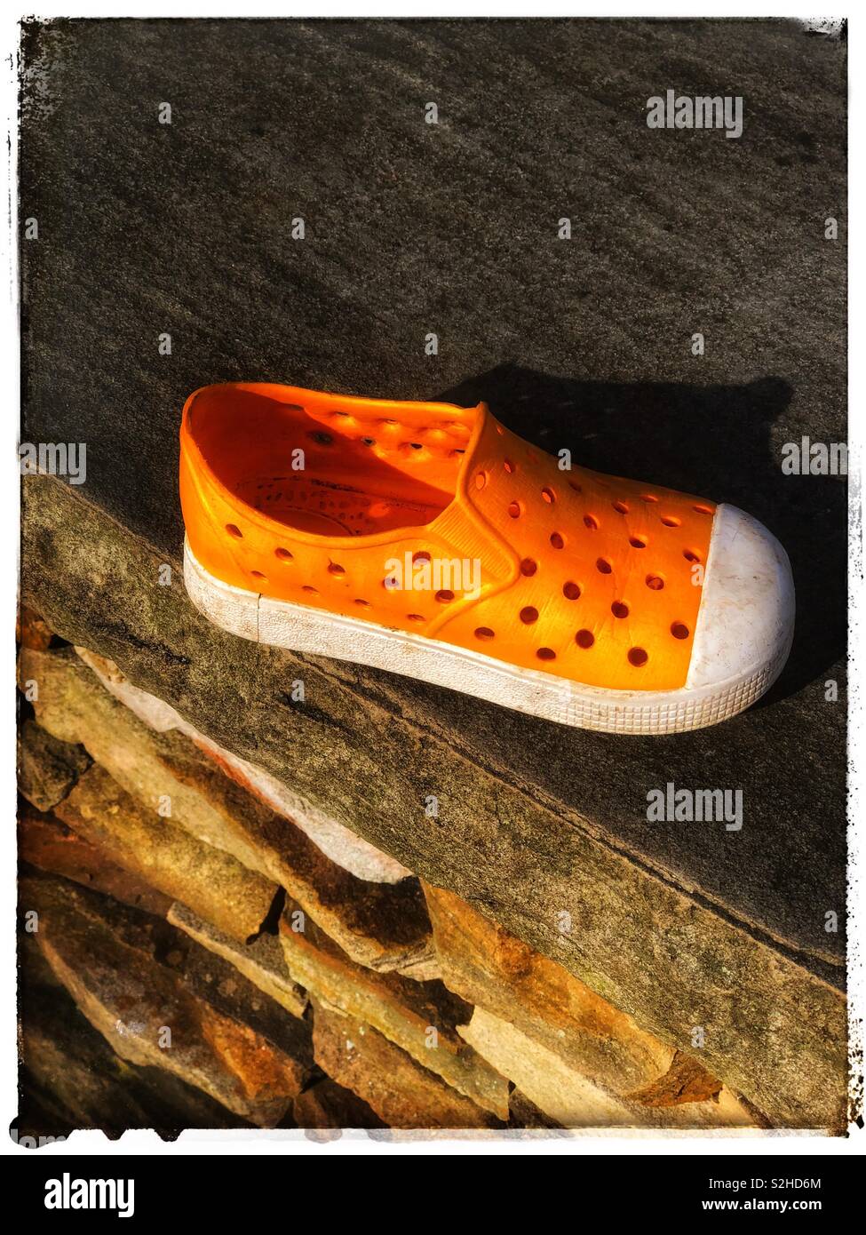 Chaussures orange avec des trous sur un mur de pierre Banque D'Images