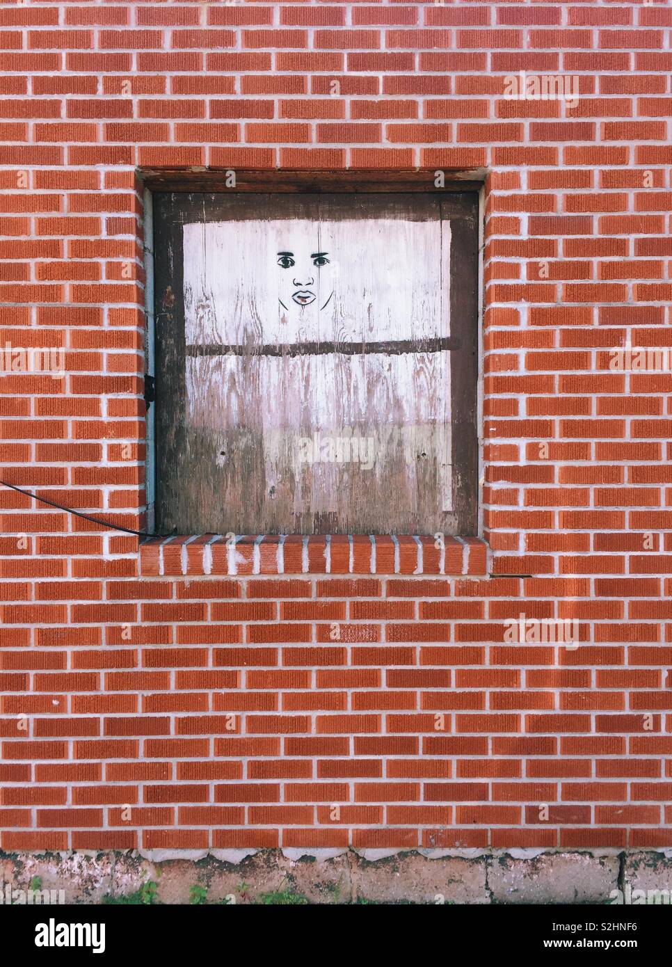 Street art fantomatique face dans la fenêtre blanche de mur de brique rouge à Hastings-on-Hudson à New York Banque D'Images