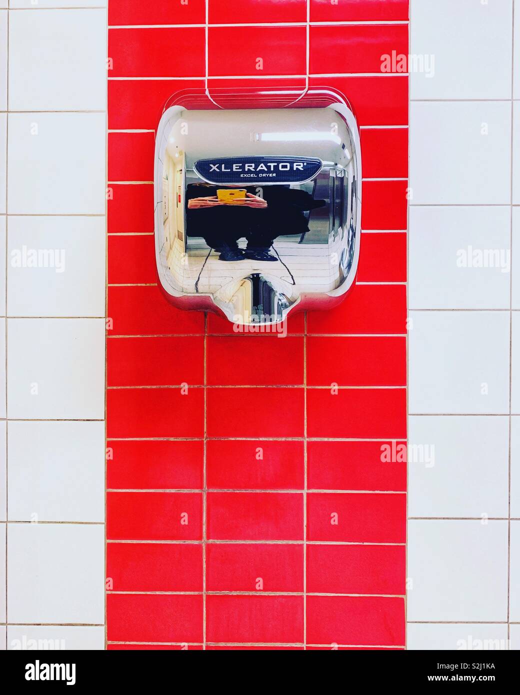 En selfies le reflet d'une toilette publique avec sèche-mains rectangulaire rouge et blanc carreaux minimaliste Banque D'Images