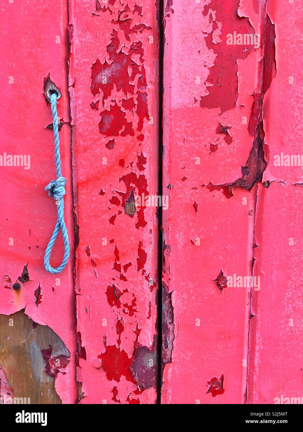 Peeling a disparu à la peinture rouge sur une ancienne porte de garage. Banque D'Images