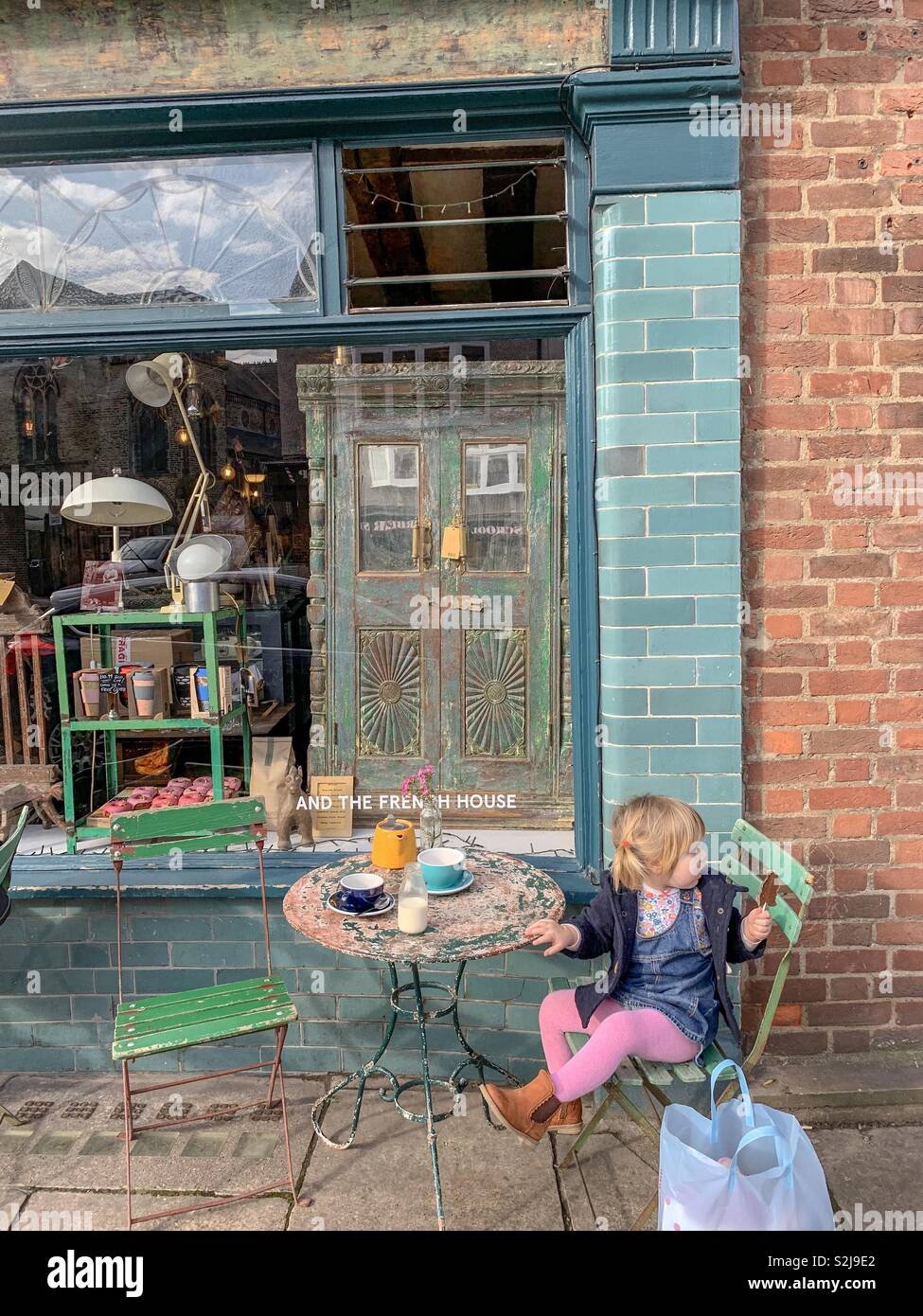 Sweet Girl se trouve à l'extérieur d'un café de New York en regardant les passants dans ses collants rose contre un carrelage vert fab café/bistro vintage avec des chaises et une table Banque D'Images