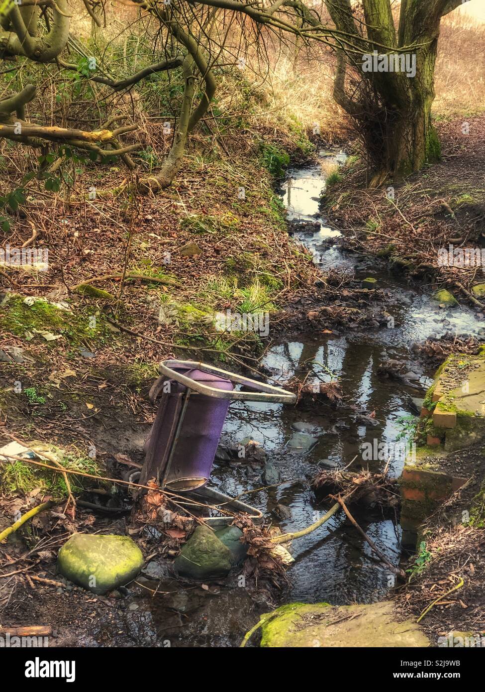 La nature menacée, alors que les gens jettent une chaise de bureau dans une petite beck, qui finira par polluer l'eau si gauche. - Image de stock capturée avec un smartphone