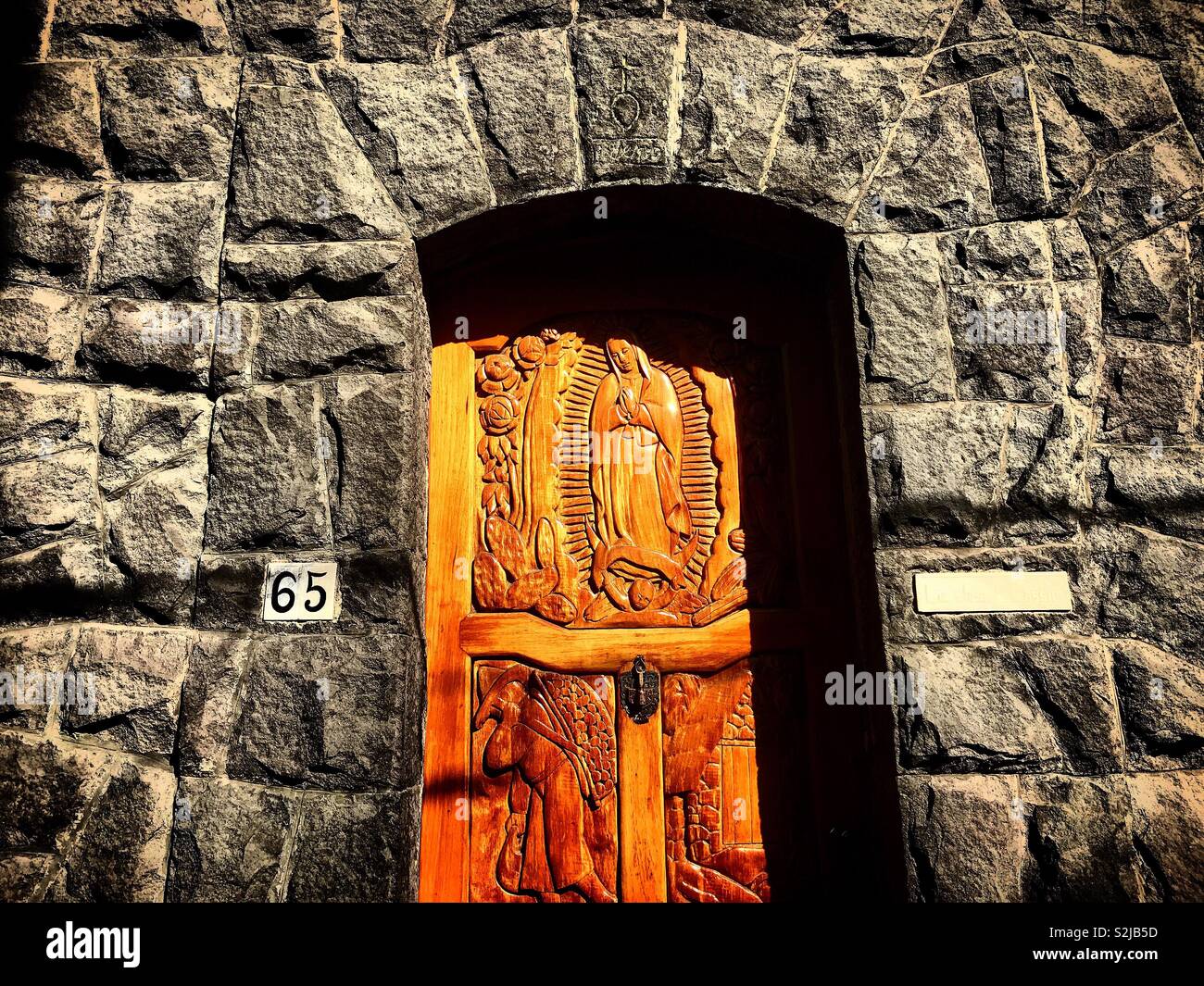 Une porte en bois sculpté avec l'image de Notre Dame de Guadalupe à Coyoacan, Mexique Banque D'Images