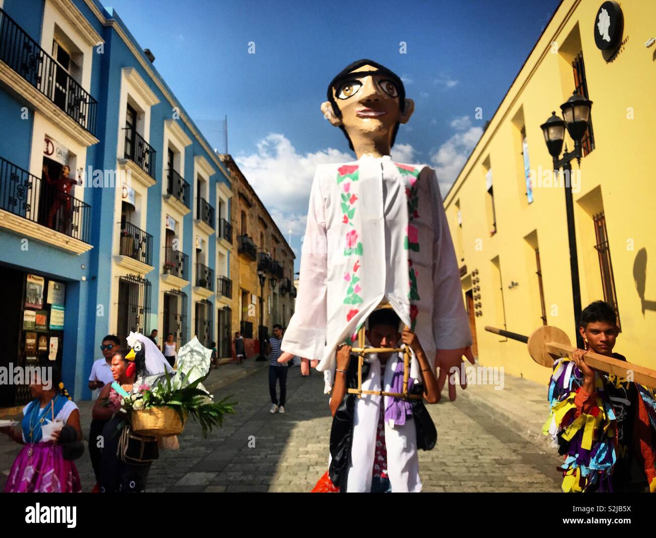 Un homme porte un gigantesque poupée en papier mâché à Oaxaca, Mexique Banque D'Images