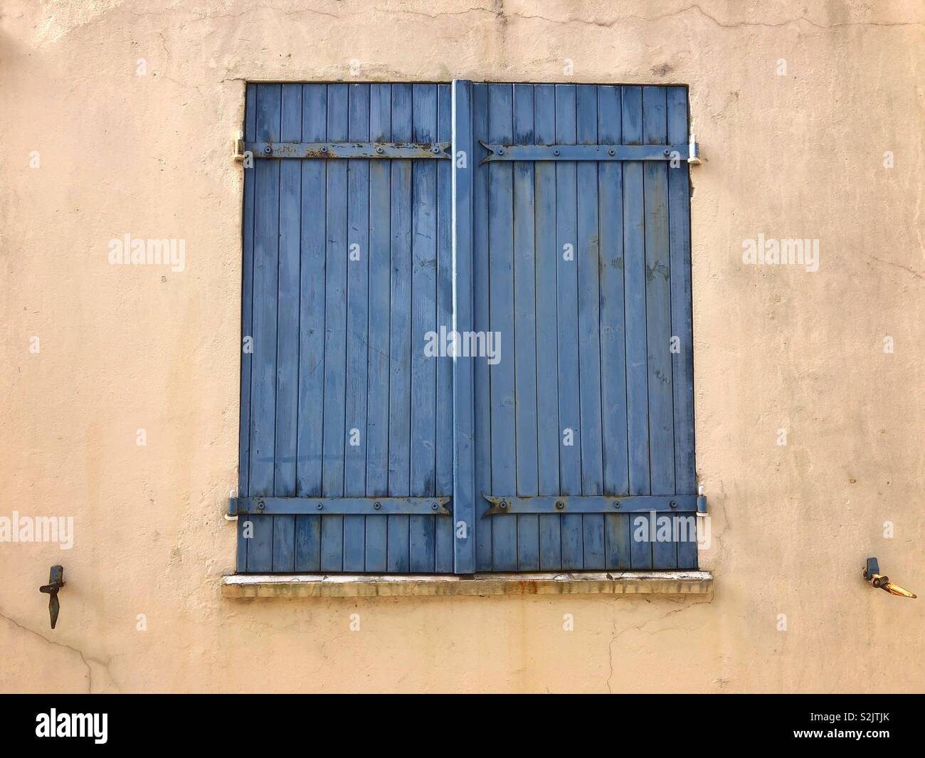 Des volets bleus sur un mur jaune, France. Banque D'Images