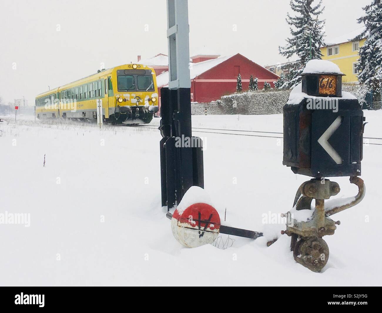 Raaberbahn train jaune-vert en hiver, boîtier de commande de l'interrupteur de fer dans l'avant-plan Banque D'Images