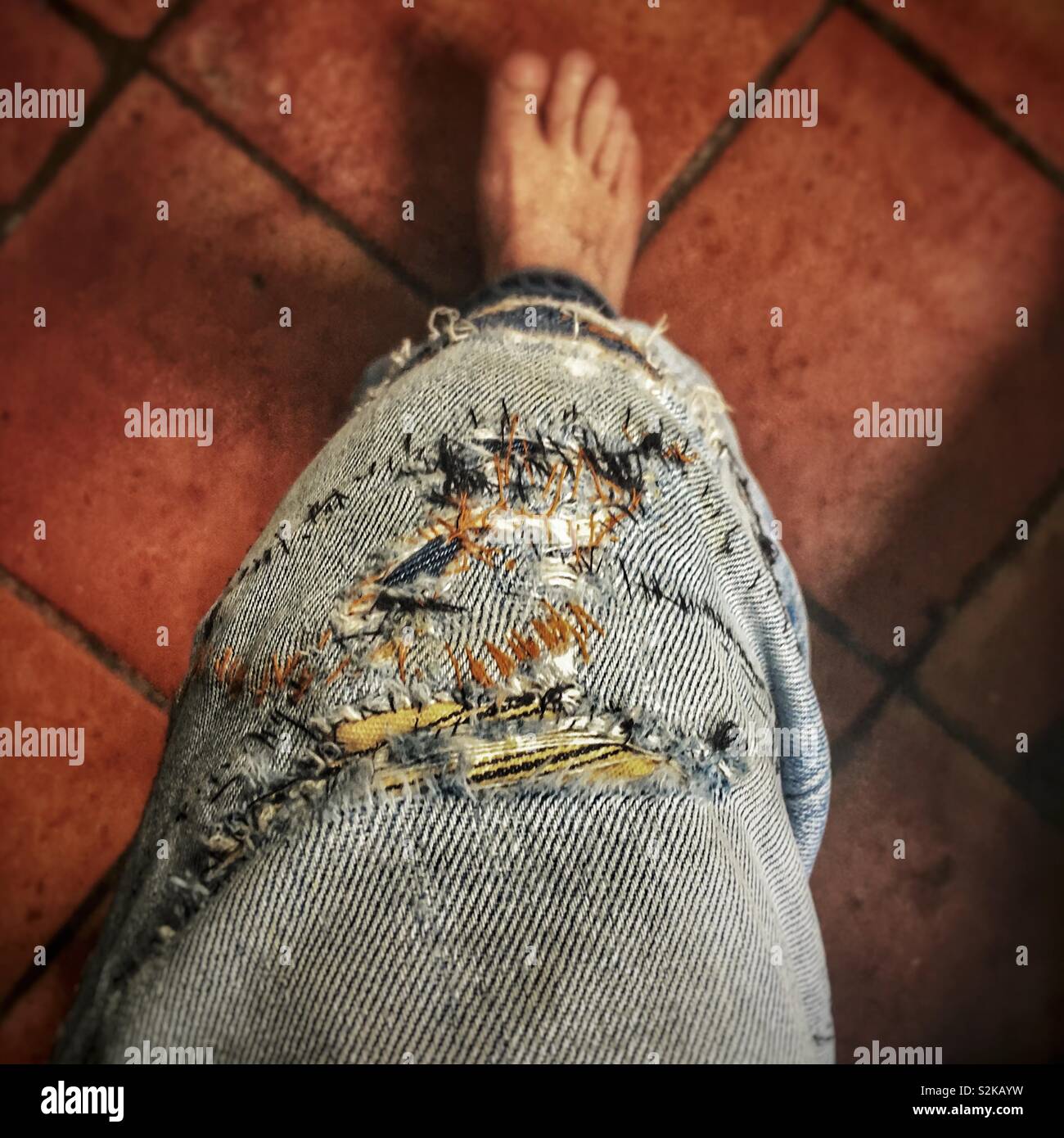 Déchiré et correction genou de vieille paire de jeans Banque D'Images
