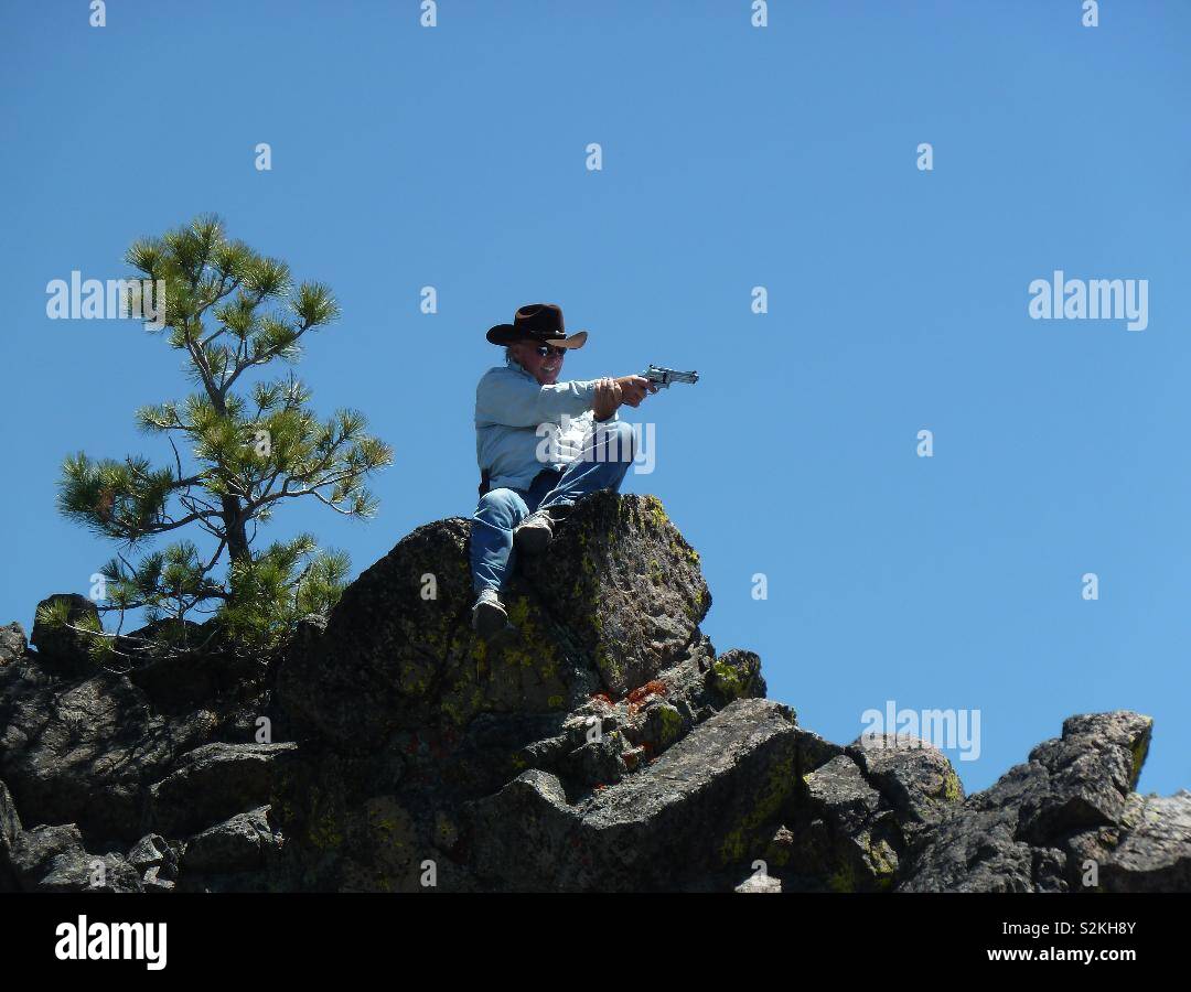 Ranch du Wyoming assise sur un rocher avec la pratique cible pistolet Smith et Wesson Banque D'Images