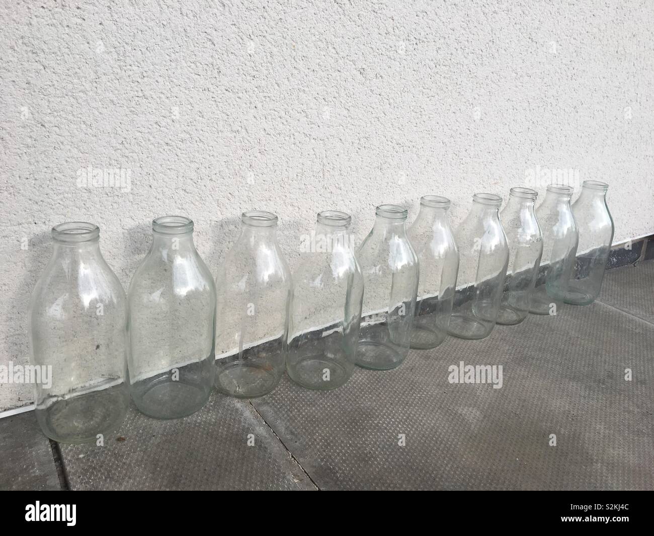 Dix bouteilles de lait vides assis par un mur - Image de stock capturée avec un smartphone