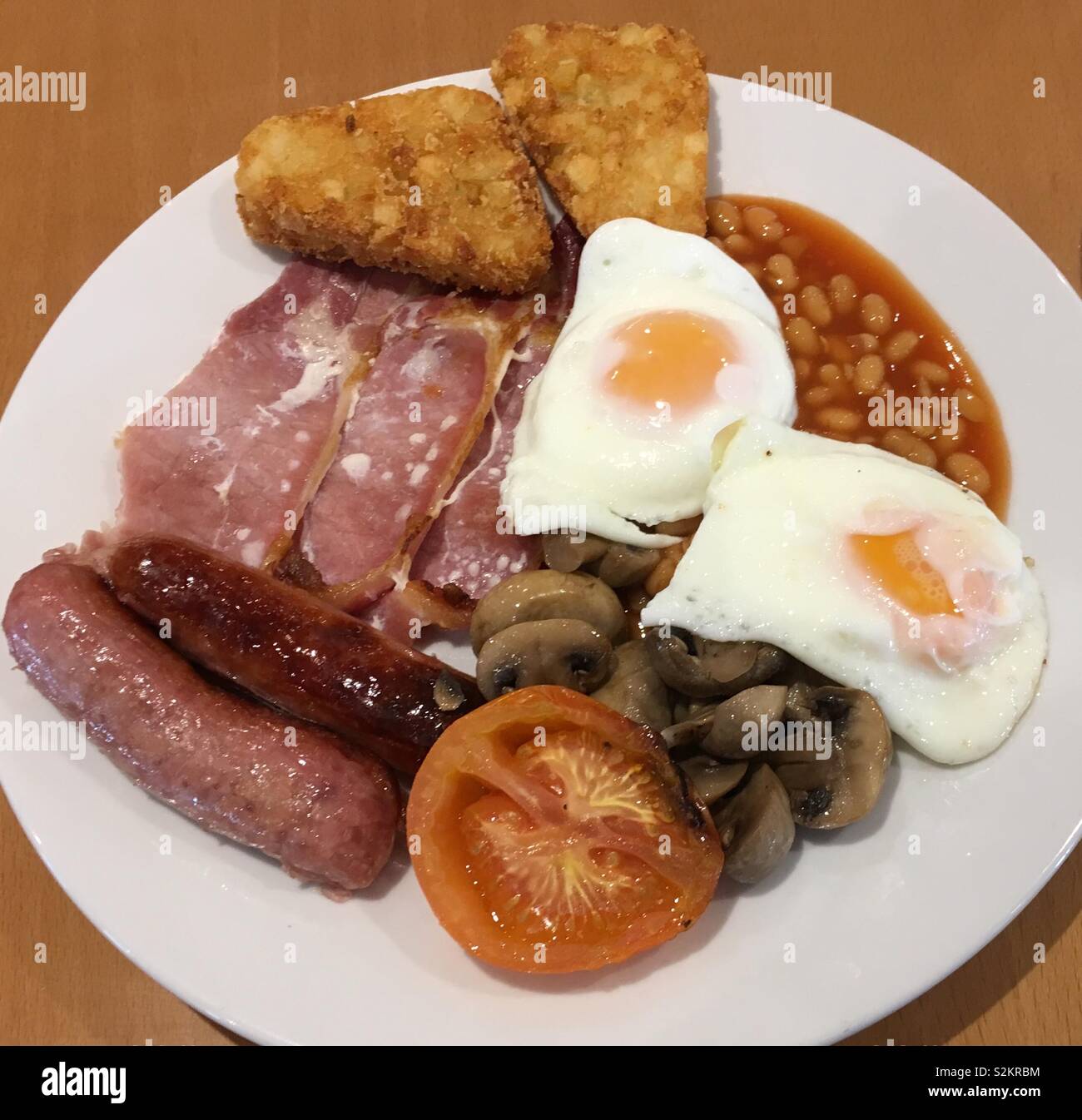 Un petit-déjeuner anglais gastronomique de bacon, d'œufs au plat, des fèves, champignons, saucisses, tomates et pommes de terre rissolées. Ce repas petit déjeuner populaire a variantes régionales et s'accompagne souvent de pain grillé. Banque D'Images