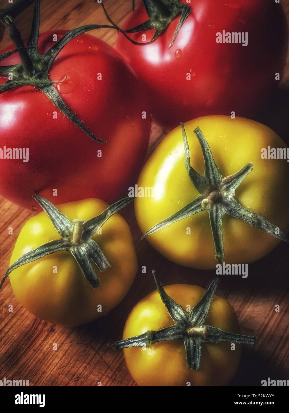 Les tomates vertes et rouges frais sur une planche à découper en bois Banque D'Images