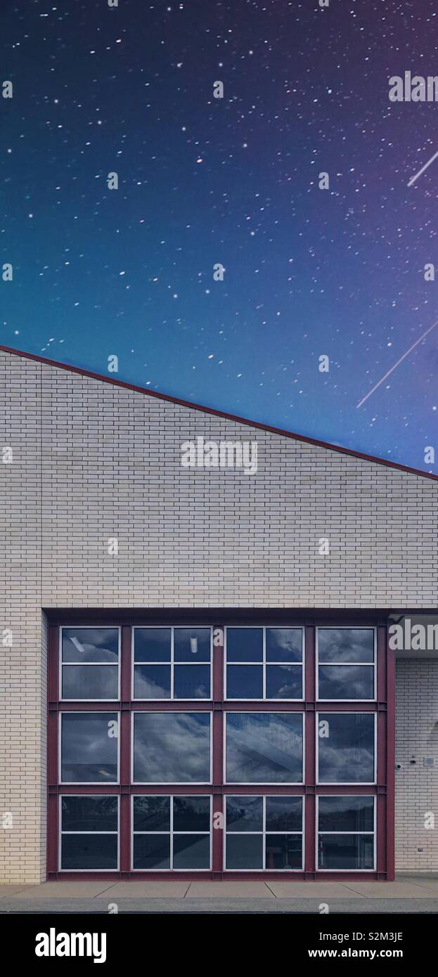 Un bâtiment avec une fenêtre qui a de nombreux volets carrés contre un ciel de nuit avec des étoiles filantes - Image de stock capturée avec un smartphone