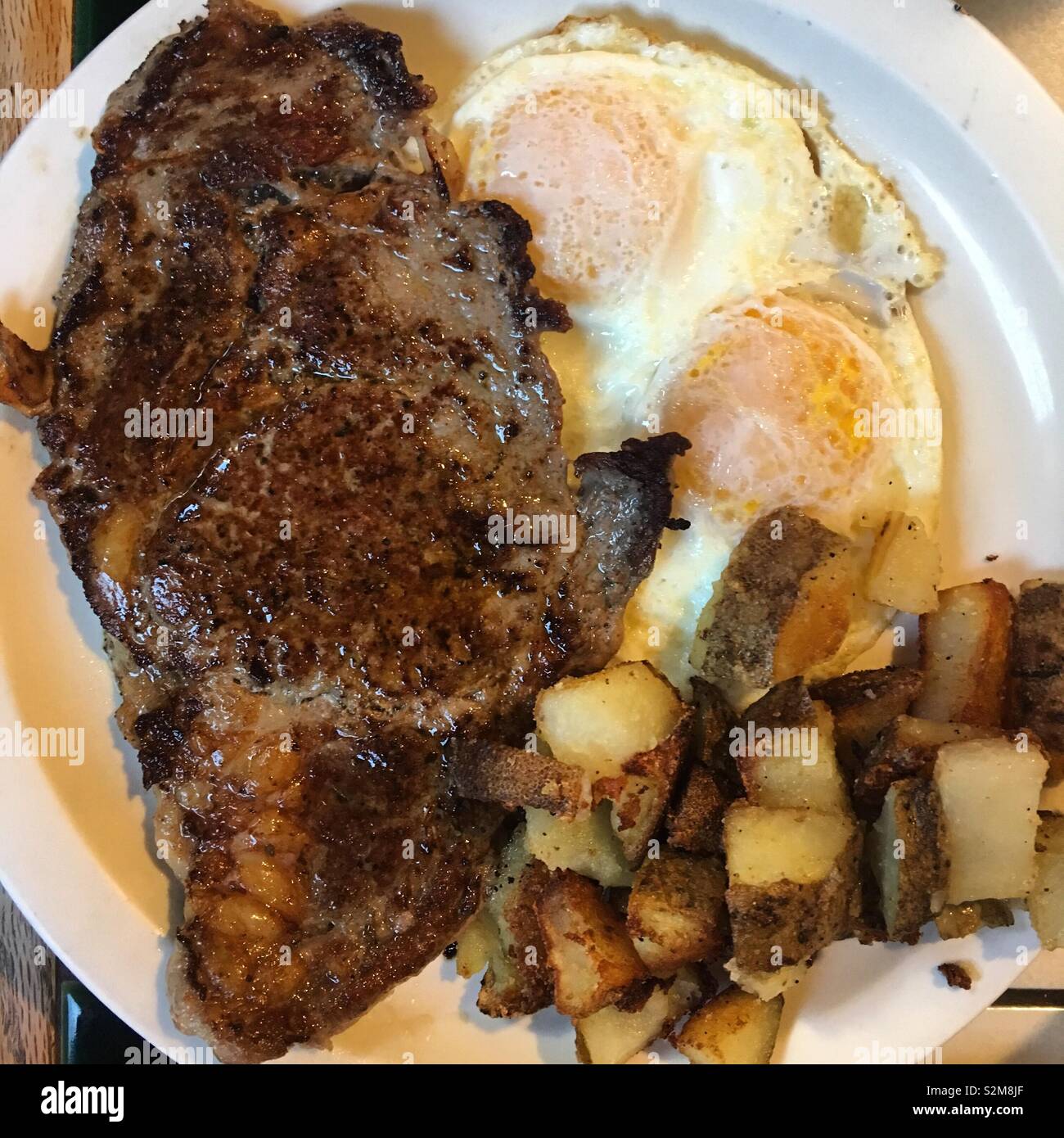 Steak et des œufs plus facile, le petit-déjeuner avec un côté de fried 'country style' pommes Banque D'Images
