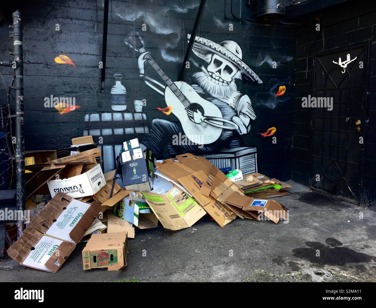 Squelette coiffé d'un sombrero à la guitare qu'à la fresque avec des piles de carton devant elle. Uptown, Oakland, Californie - Image de stock capturée avec un smartphone