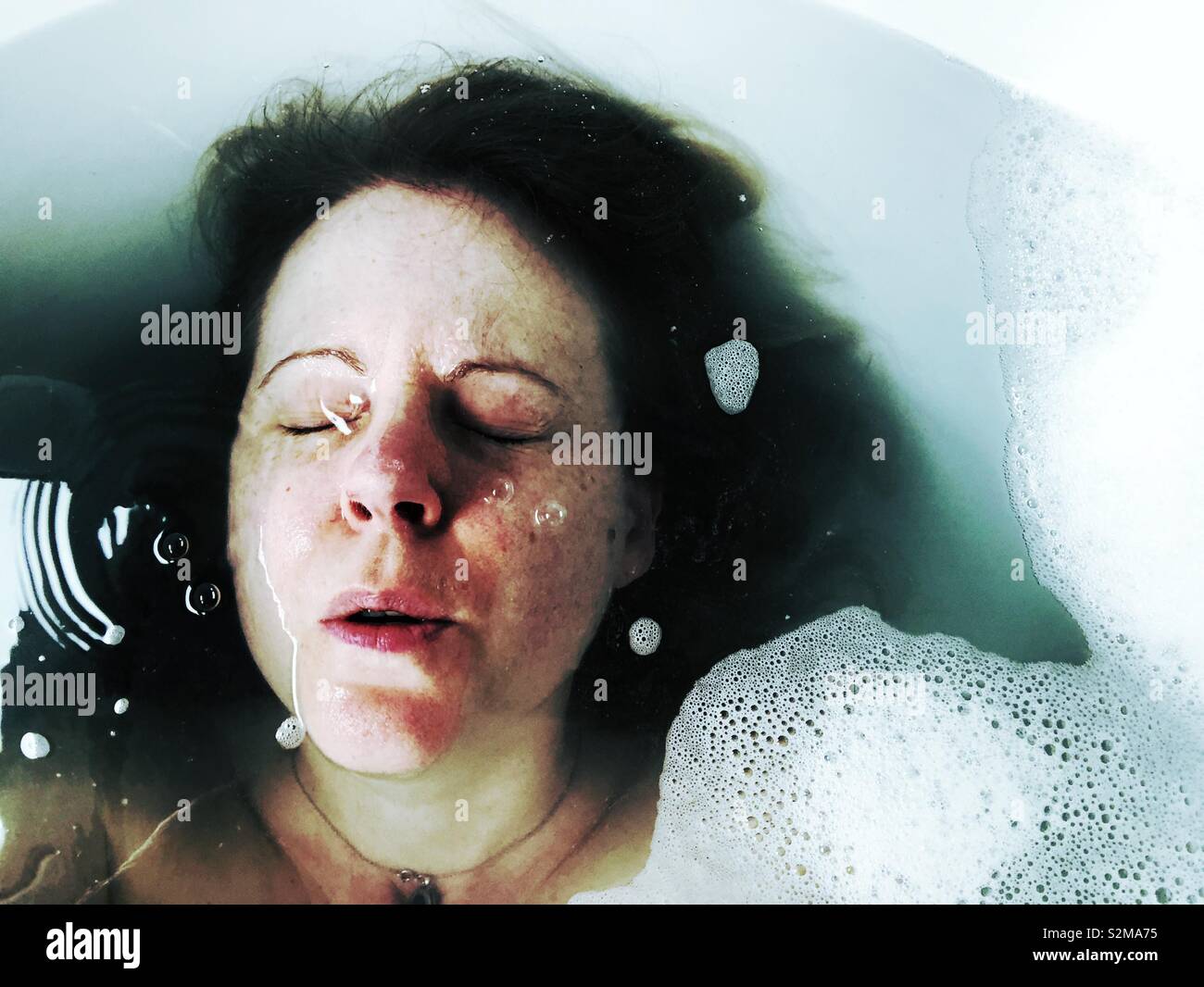 Femme de mettre la tête sous l'eau dans un bain de mousse Banque D'Images