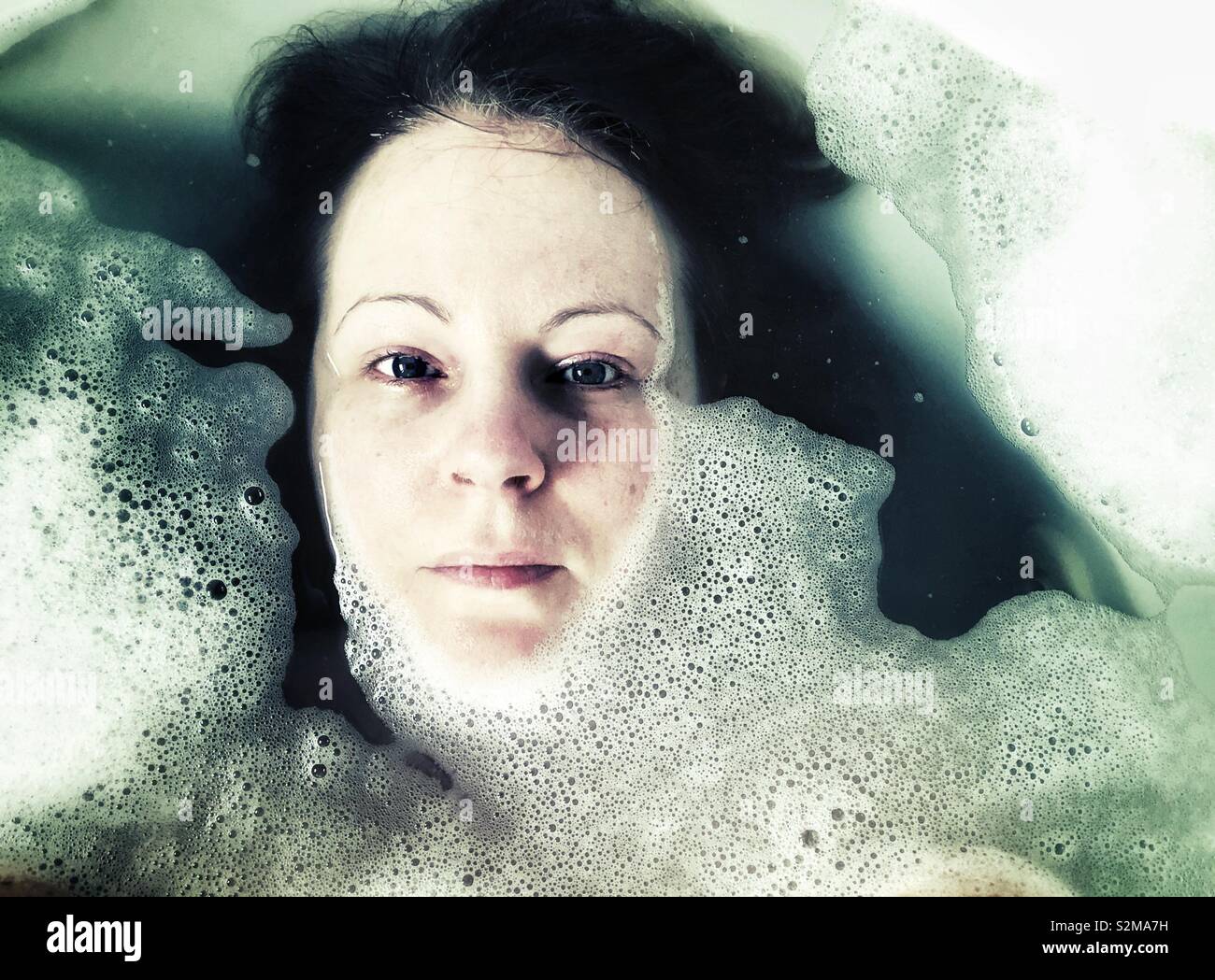 Visage de femme dans un bain de mousse looking at camera Banque D'Images