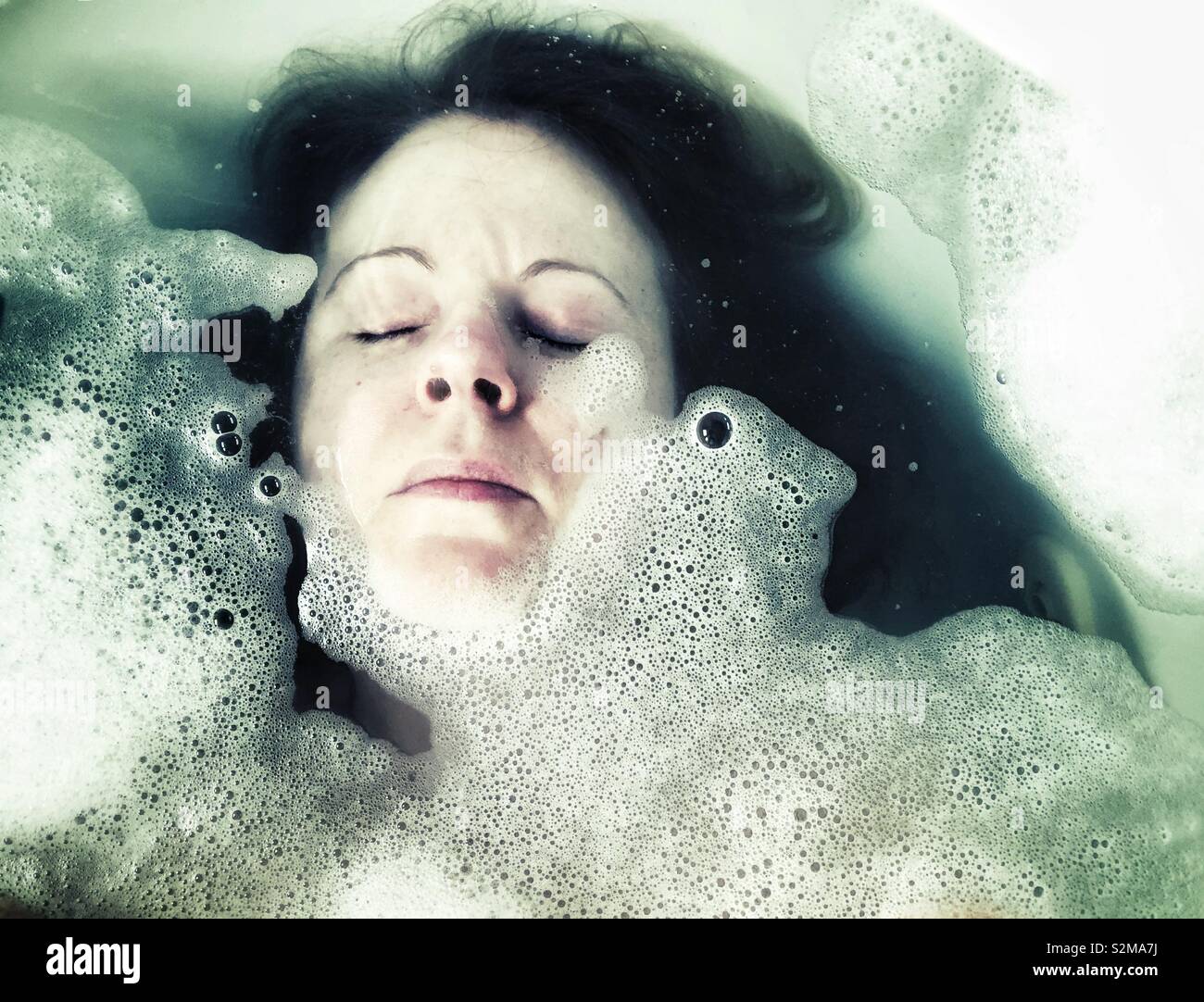 Visage femme plonger sous l'eau dans un bain de mousse Banque D'Images
