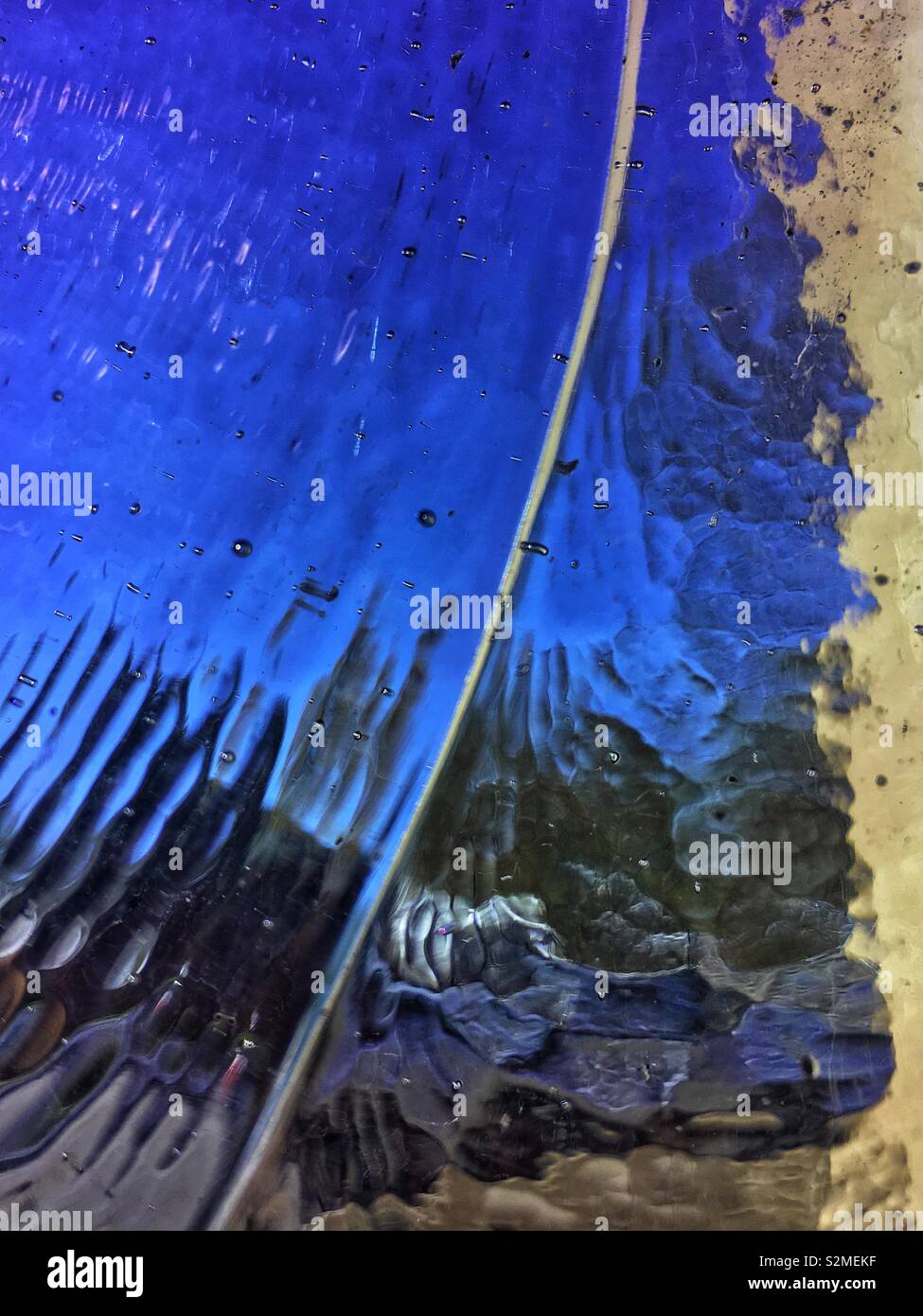 Vitraux colorés décoratifs en verre translucide bleu texturé avec un motif abstrait aléatoire. Banque D'Images