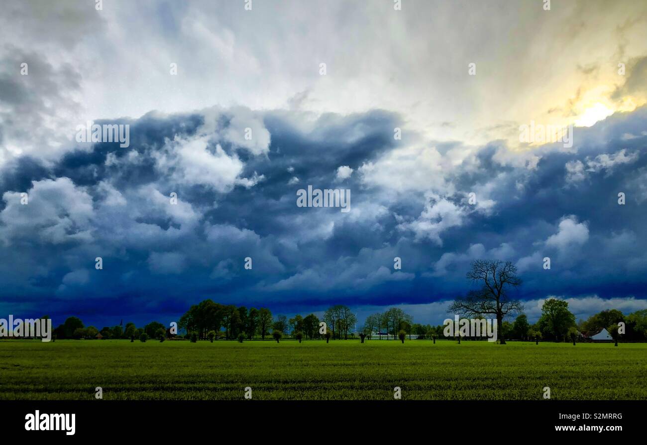 Bien briser derrière et au-dessus de la spectaculaire et de sombres nuages sur un paysage de campagne d'herbe verte - Image de stock capturée avec un smartphone