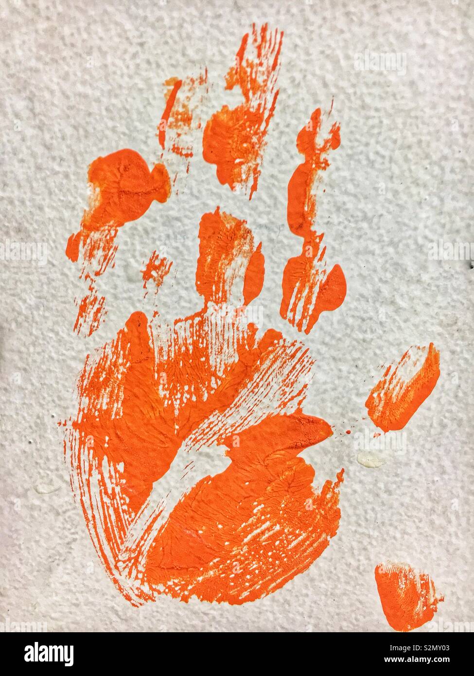 La main gauche de l'enfant dans la peinture orange imprimer en utilisant les techniques de peinture à la main. Banque D'Images
