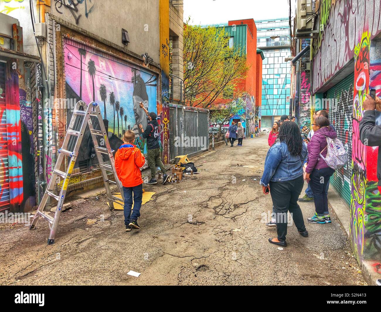 Regarder l'artiste au travail dans l'écriture Graffiti Alley, Toronto, Canada. - Image de stock capturée avec un smartphone