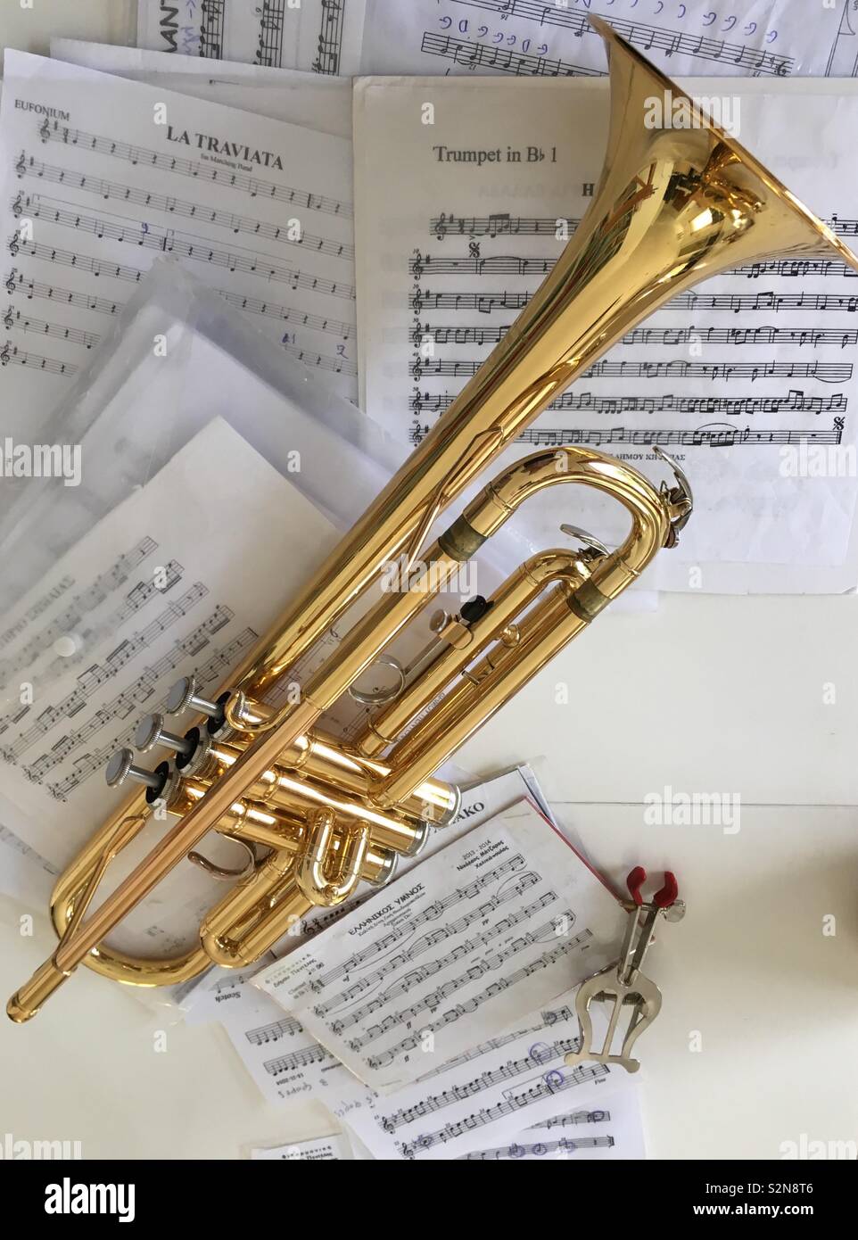 Nouvelle trompette flambant neuve de garçon de 12 ans posée sur une table au milieu de feuilles de musique trompette et le détenteur de musique, prêt pour une leçon de trompette imminente. Banque D'Images