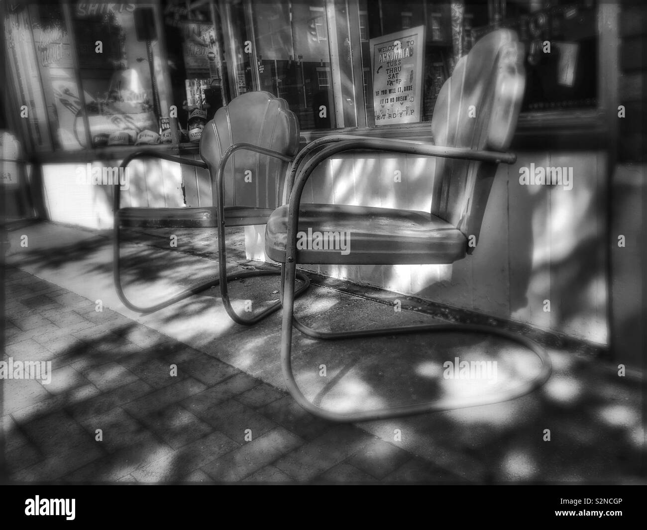 Vintage metal chaises en face d'un centre-ville magasin vintage Banque D'Images