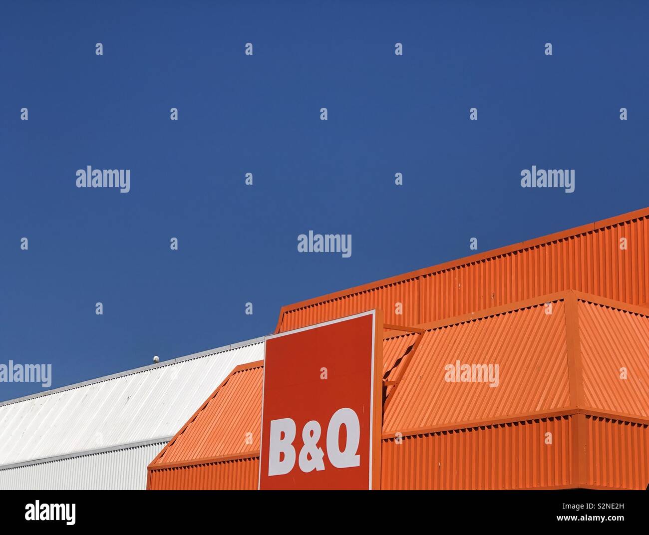 Résumé formé par le ciel bleu, et l'orange et blanc distinctif extérieur de B&Q magasin de bricolage - Image de stock capturée avec un smartphone