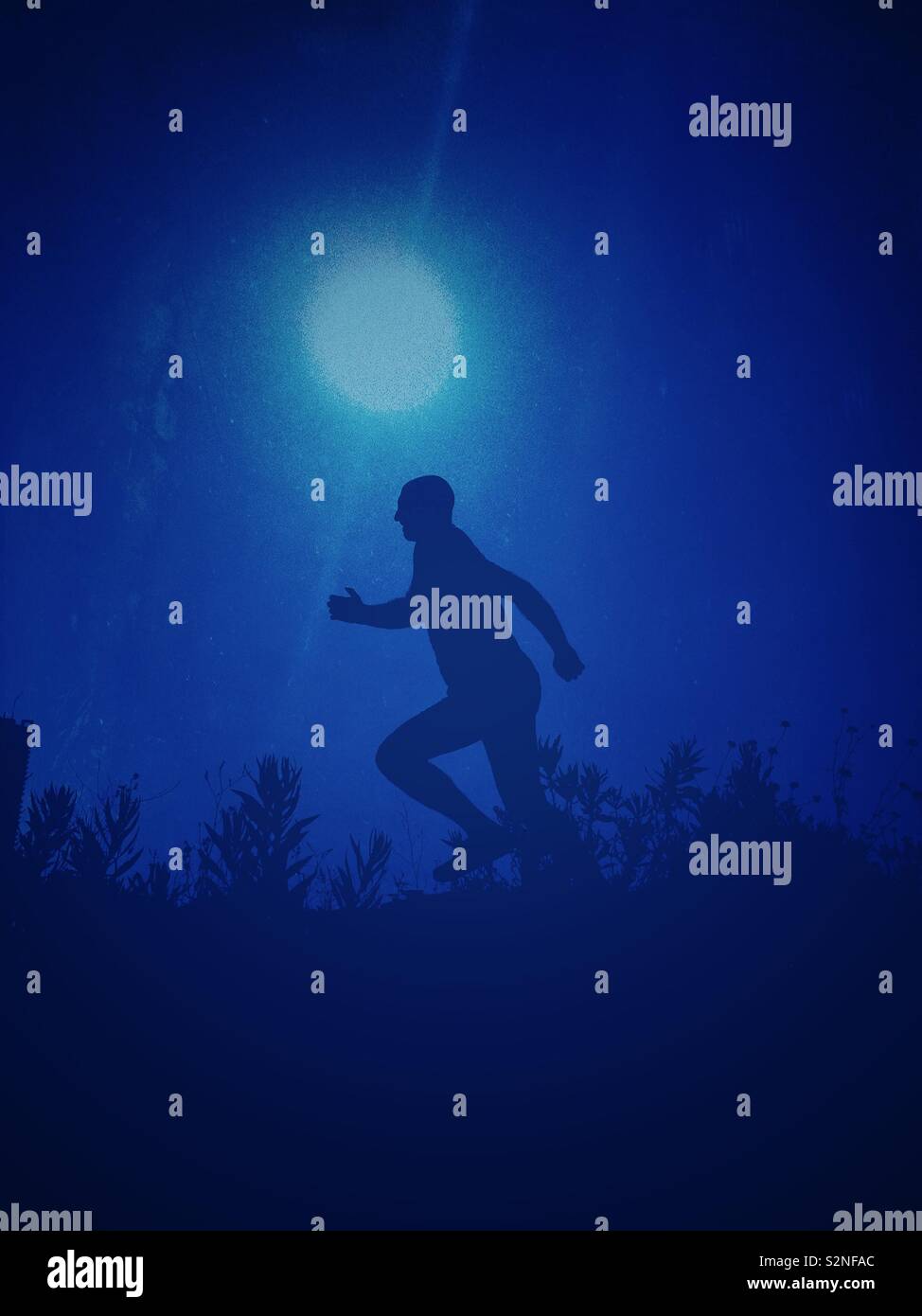 Homme qui court dans le champ à la nuit Banque D'Images