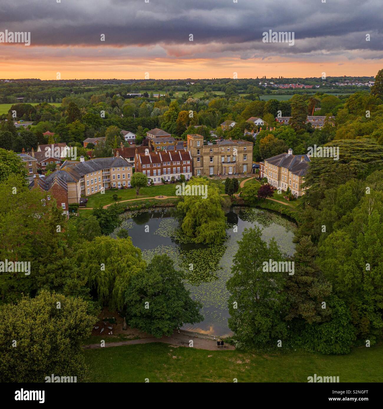 Un jeune couple assis sur un banc en face d'un lac et d'une belle rangée de maisons sous un ciel de coucher du soleil - Image de stock capturée avec un smartphone