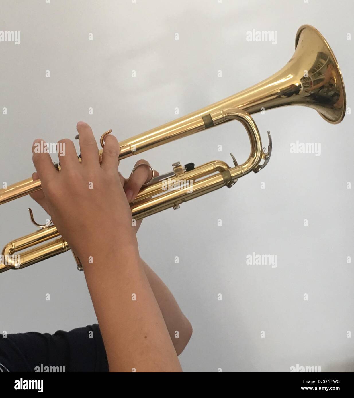 Enthousiaste garçon de 12 ans pratiquant sur sa nouvelle trompette brillante avant sa leçon de trompette et la pratique d'orchestre. Banque D'Images