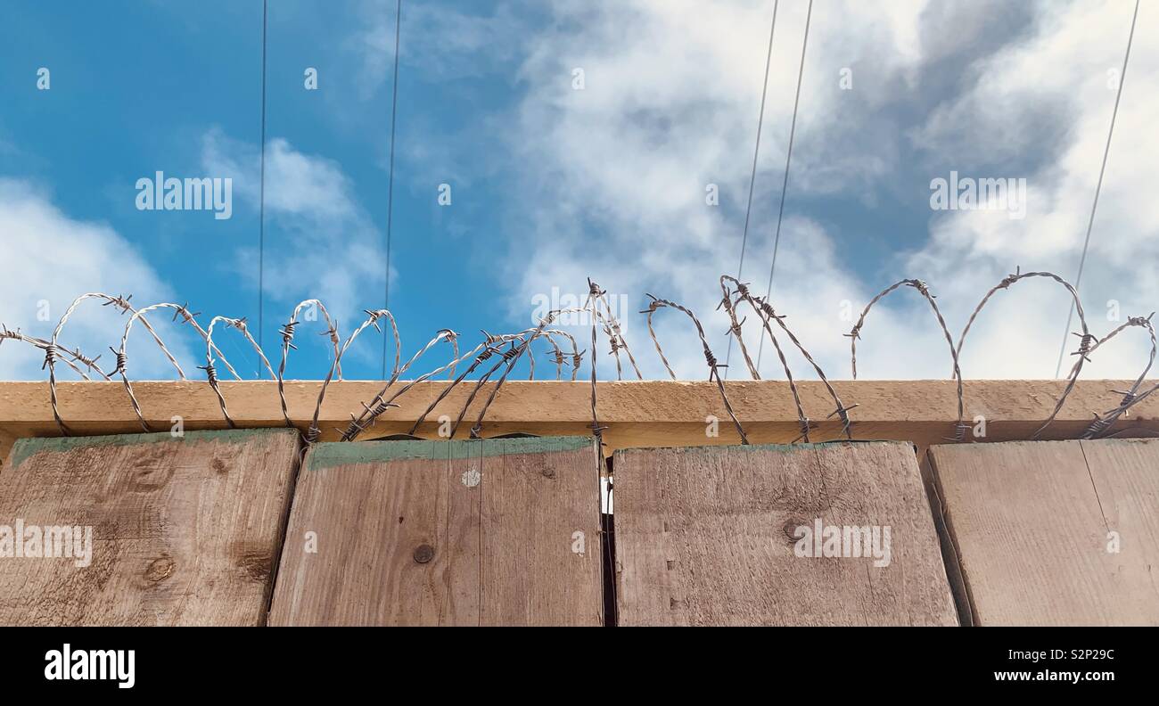 Planche en bois clôture avec barbelés haut against sky Banque D'Images