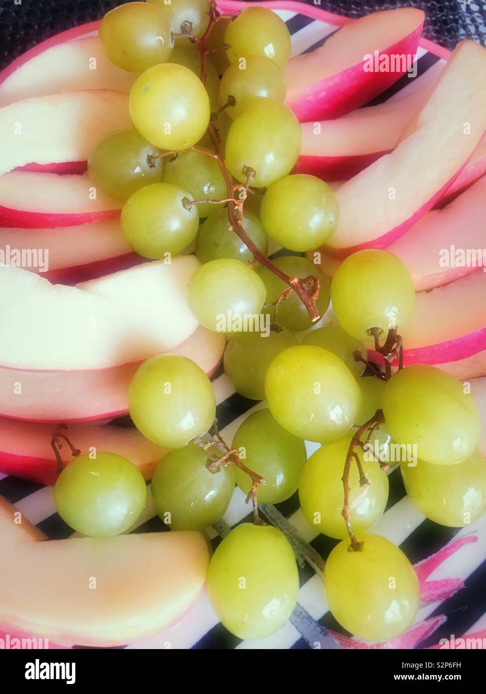 Télévision lay close up de raisins et les tranches de pommes sur une assiette. - Image de stock capturée avec un smartphone