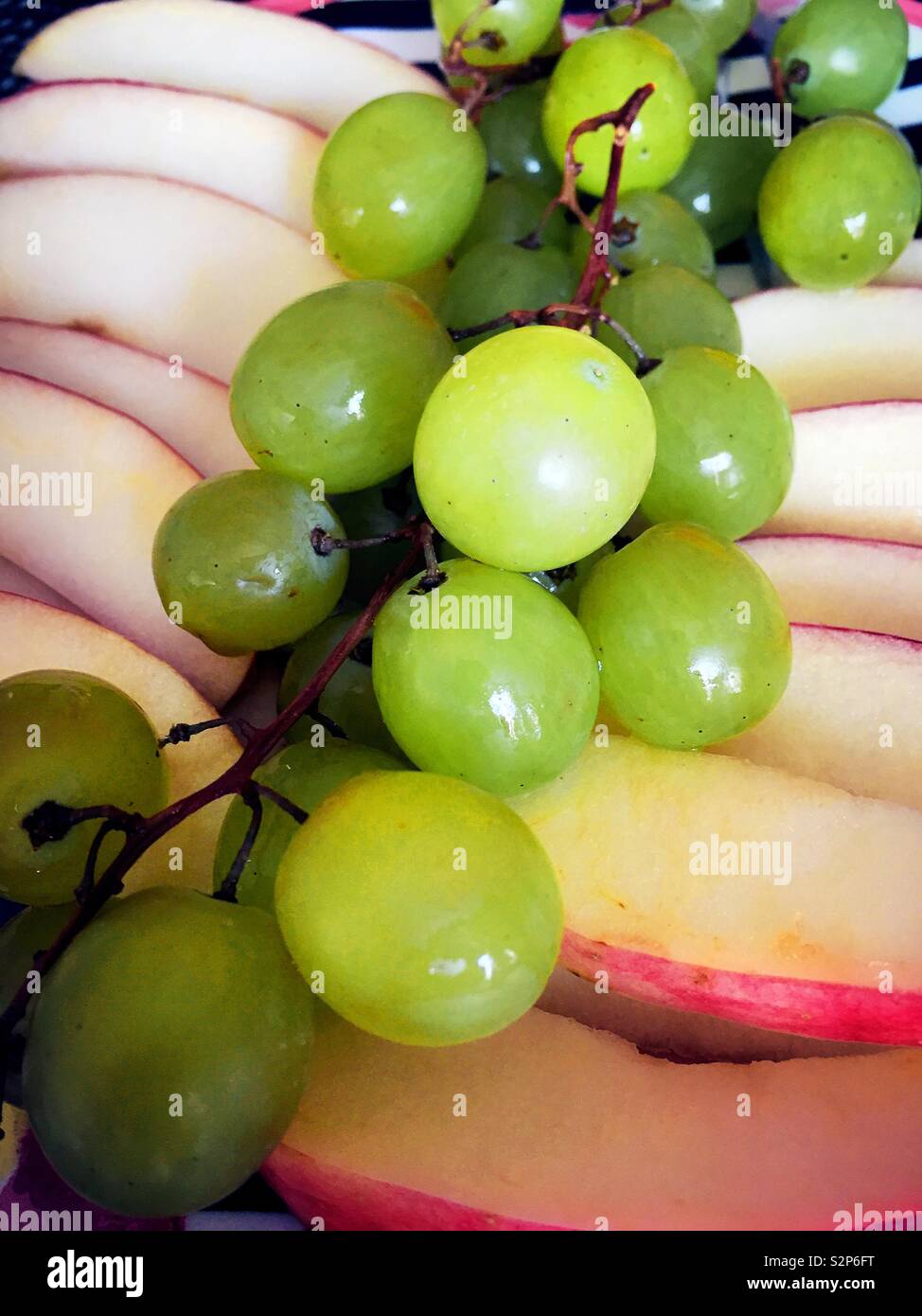 Lac plat close up de raisins et les tranches de pommes sur une assiette - Image de stock capturée avec un smartphone