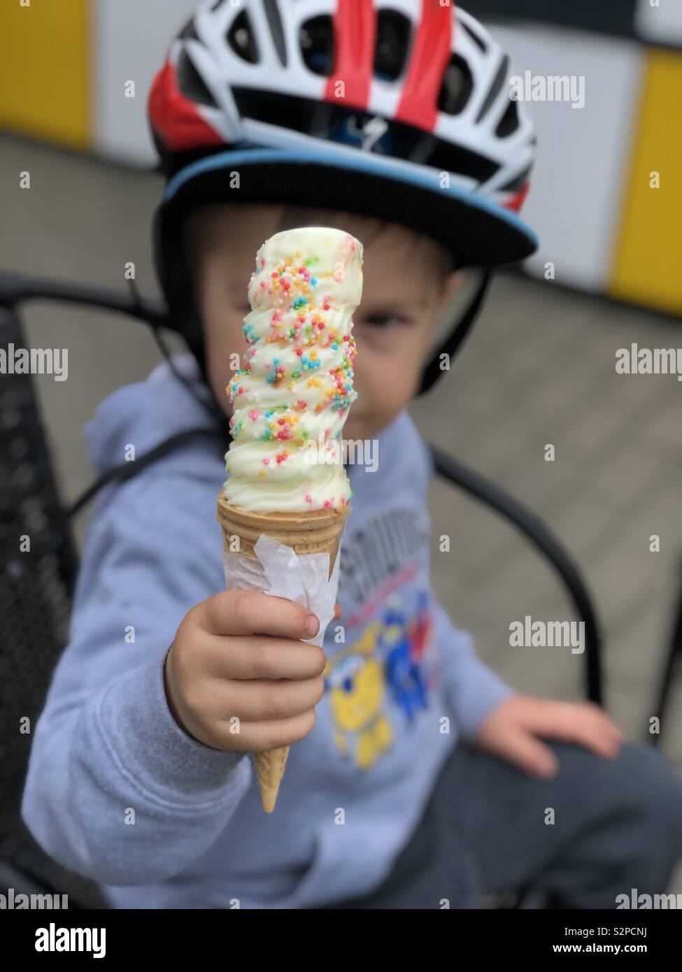 Toddler eating ice cream with Sprinkles dehors avec un casque de vélo sur Banque D'Images