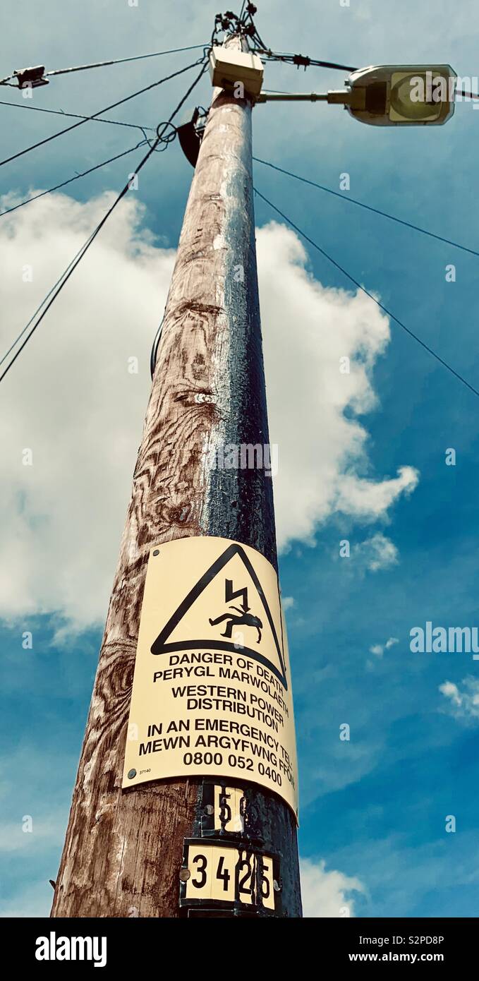 Poteau d' électricité avec bi-lingue Anglais/Gallois panneau d'avertissement de danger de mort Banque D'Images