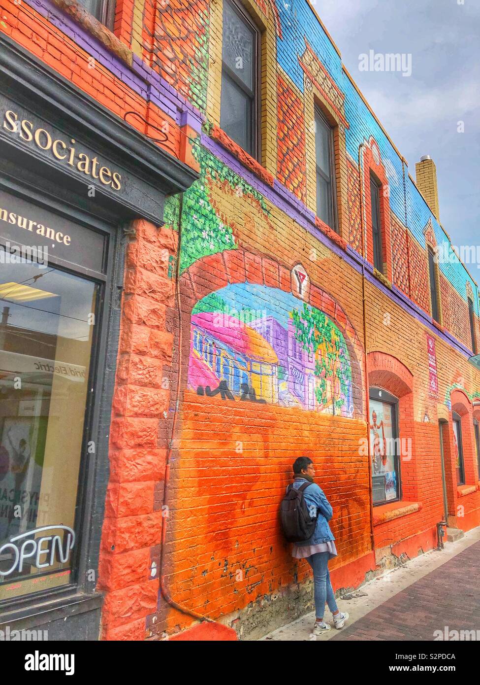 Une jeune femme appuyée contre un mur de briques colorées. - Image de stock capturée avec un smartphone
