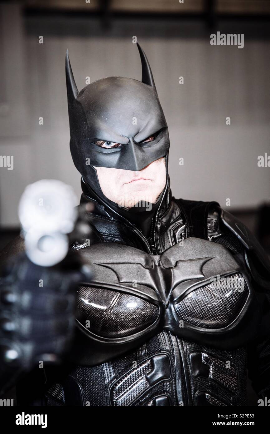 Un portrait d'un homme portant un costume de Batman cosplayeur et tient une arme à l'appareil photo tout en un événement comic con Banque D'Images