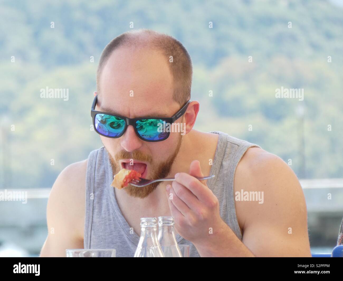 Un homme de manger en été, porter des lunettes et une veste en miroir Banque D'Images