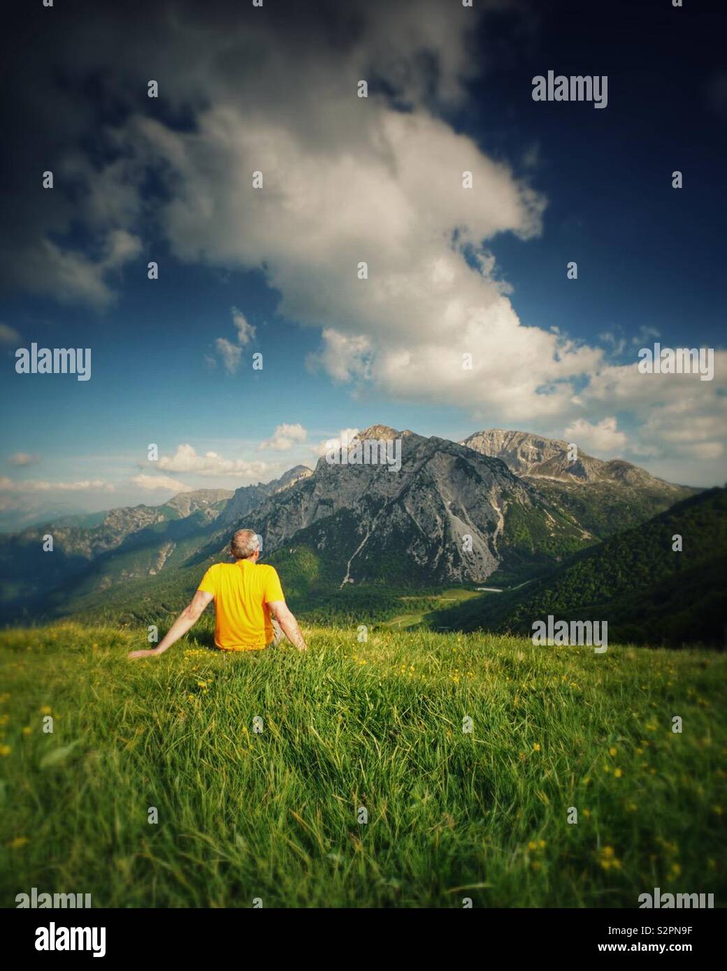 Homme assis sur l'herbe à la montagne à Banque D'Images